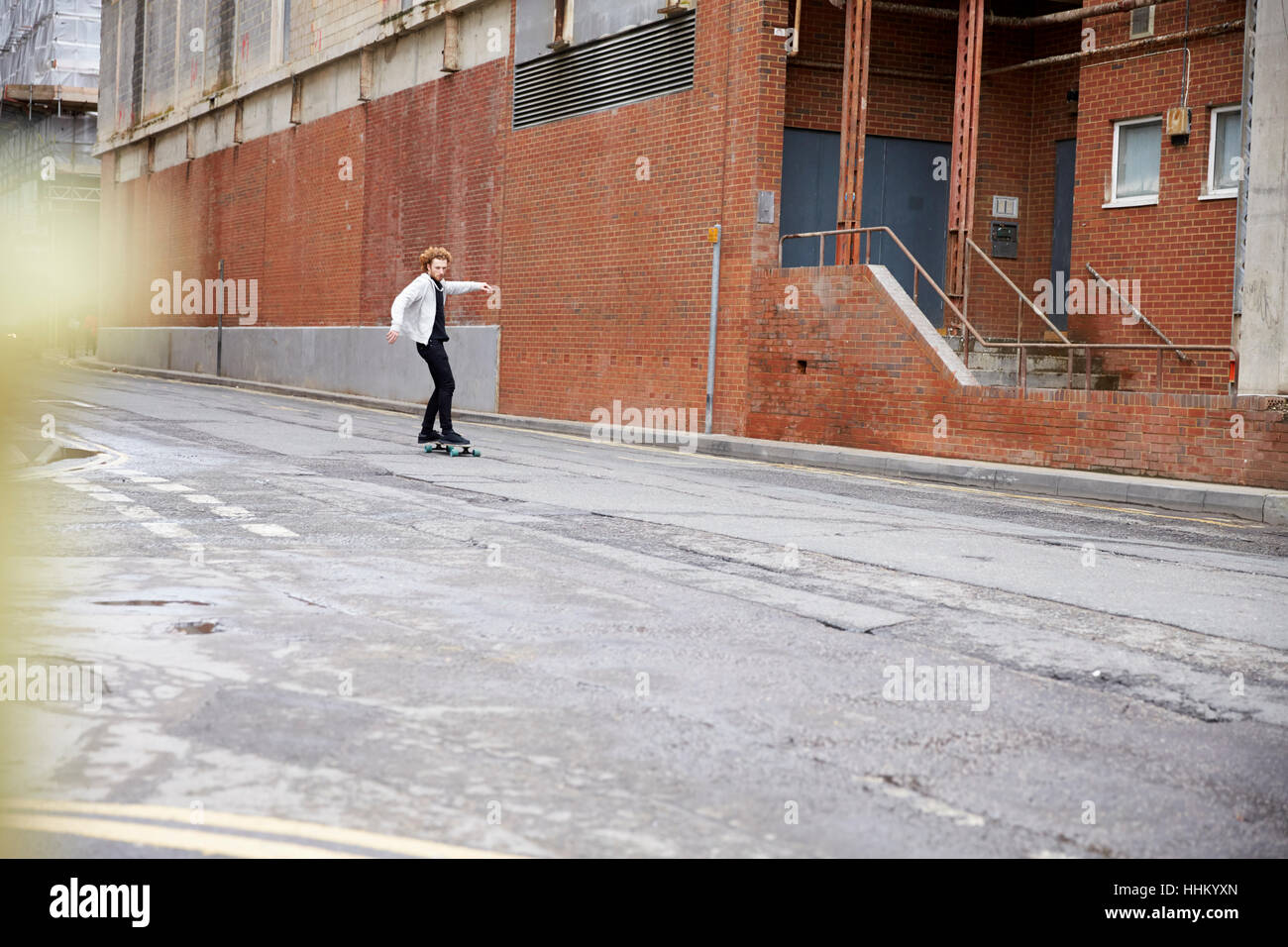 Distant red haired man skateboarding on an urban road Stock Photo