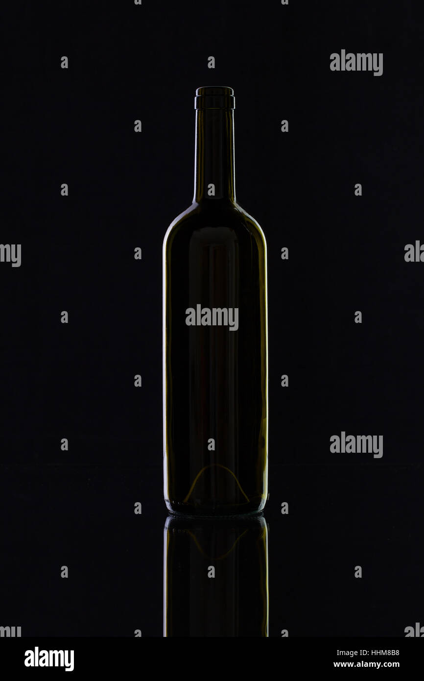 Silhouette of elegant and very old wine bottle on a glass table Stock Photo