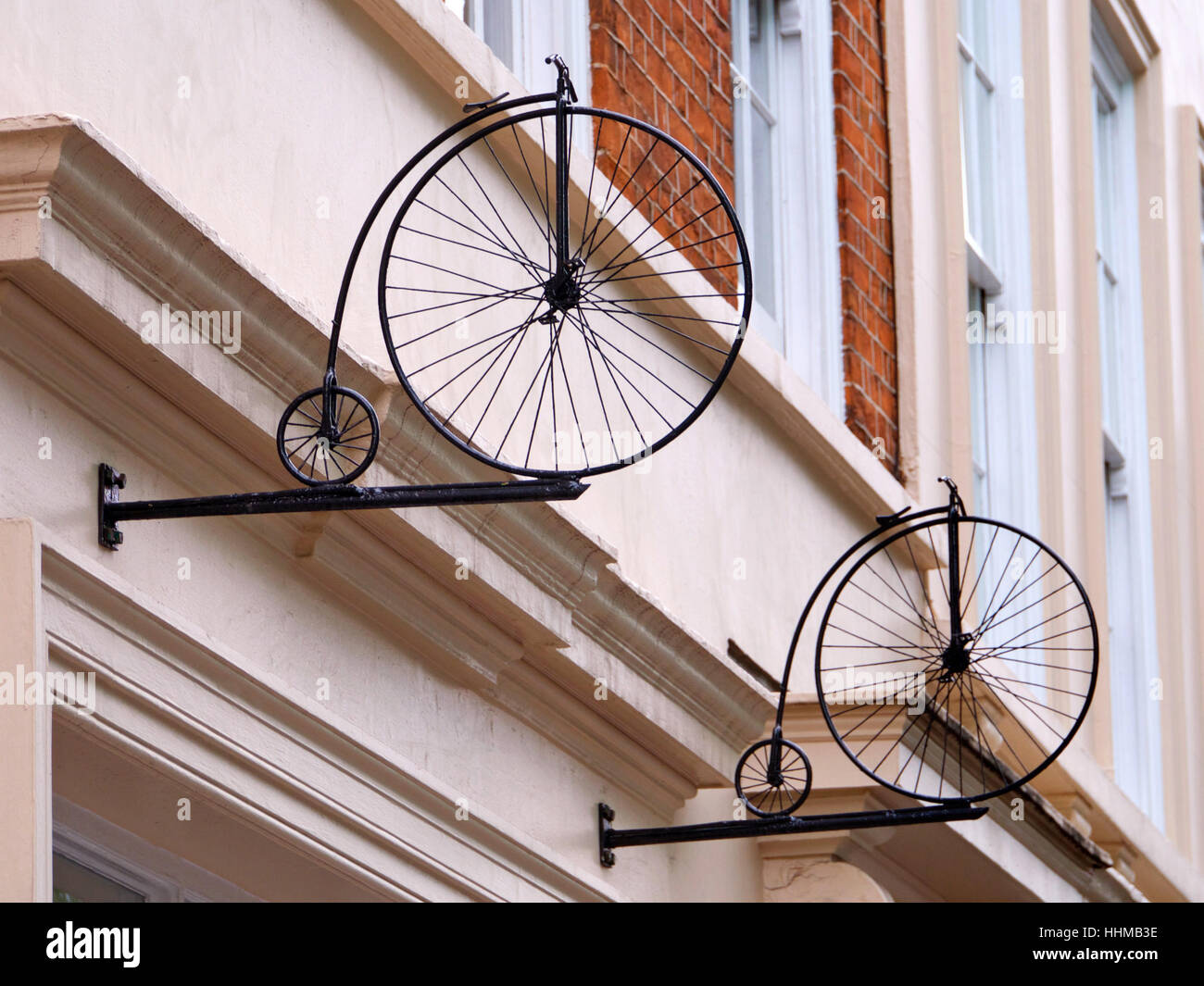 Mini Penny Farthing bicycles mounted on wall in Soho, London Stock Photo