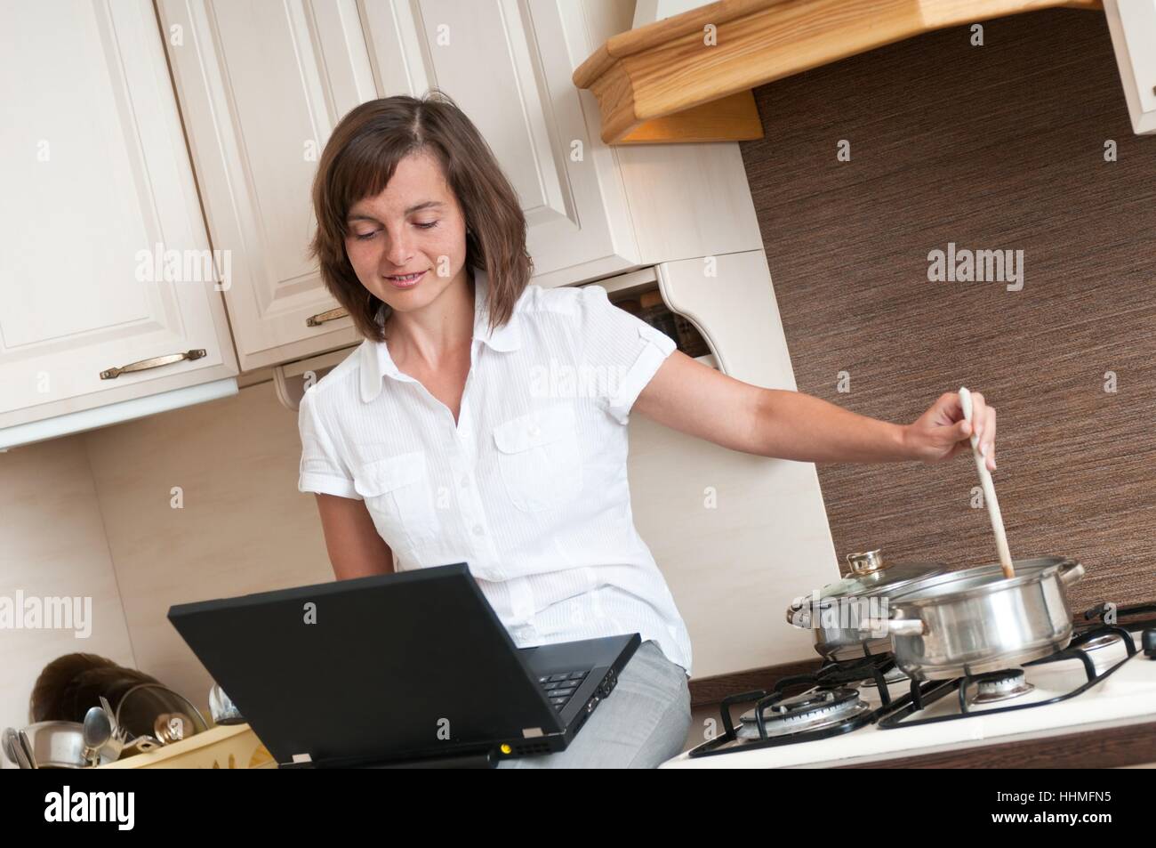 Multitasking woman cooking meal working hi-res stock photography and ...