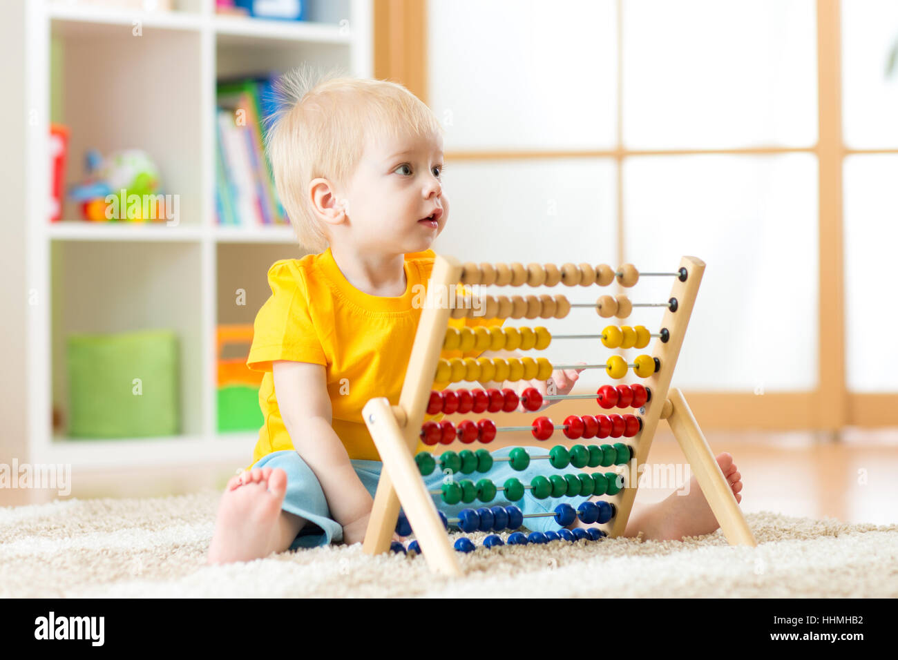 Preschooler baby learns to count. Cute child playing with abacus toy. Little boy having fun indoors at kindergarten, playschool, home or daycare centre. Educational concept for preschool kids. Stock Photo