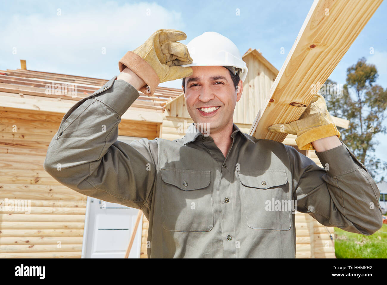 Skilled worker working at construction site and carries wood Stock Photo