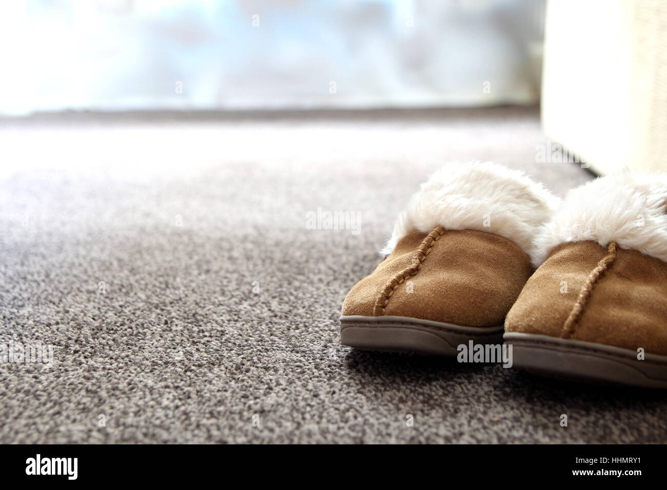 Generic ladies suede slippers on carpet next to sofa in a nice living room. Copy space for text. Stock Photo