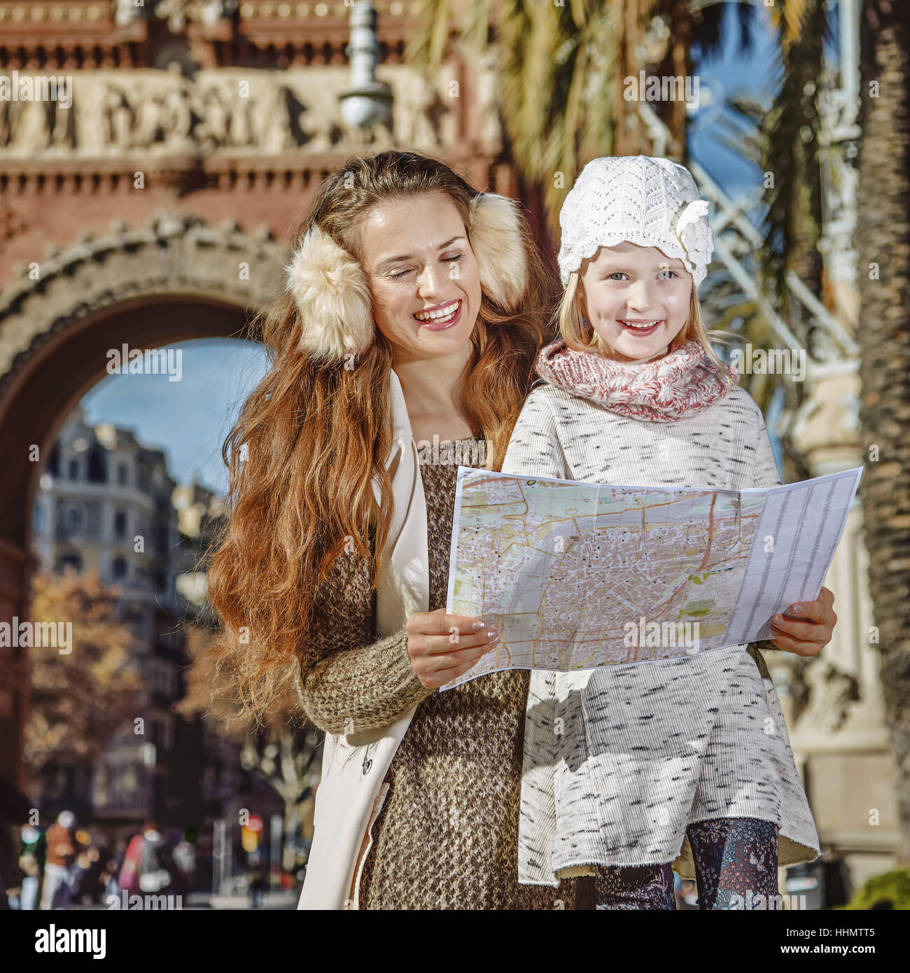 in Barcelona for a perfect winter. smiling modern mother and daughter near Arc de Triomf in Barcelona, Spain looking at the map Stock Photo