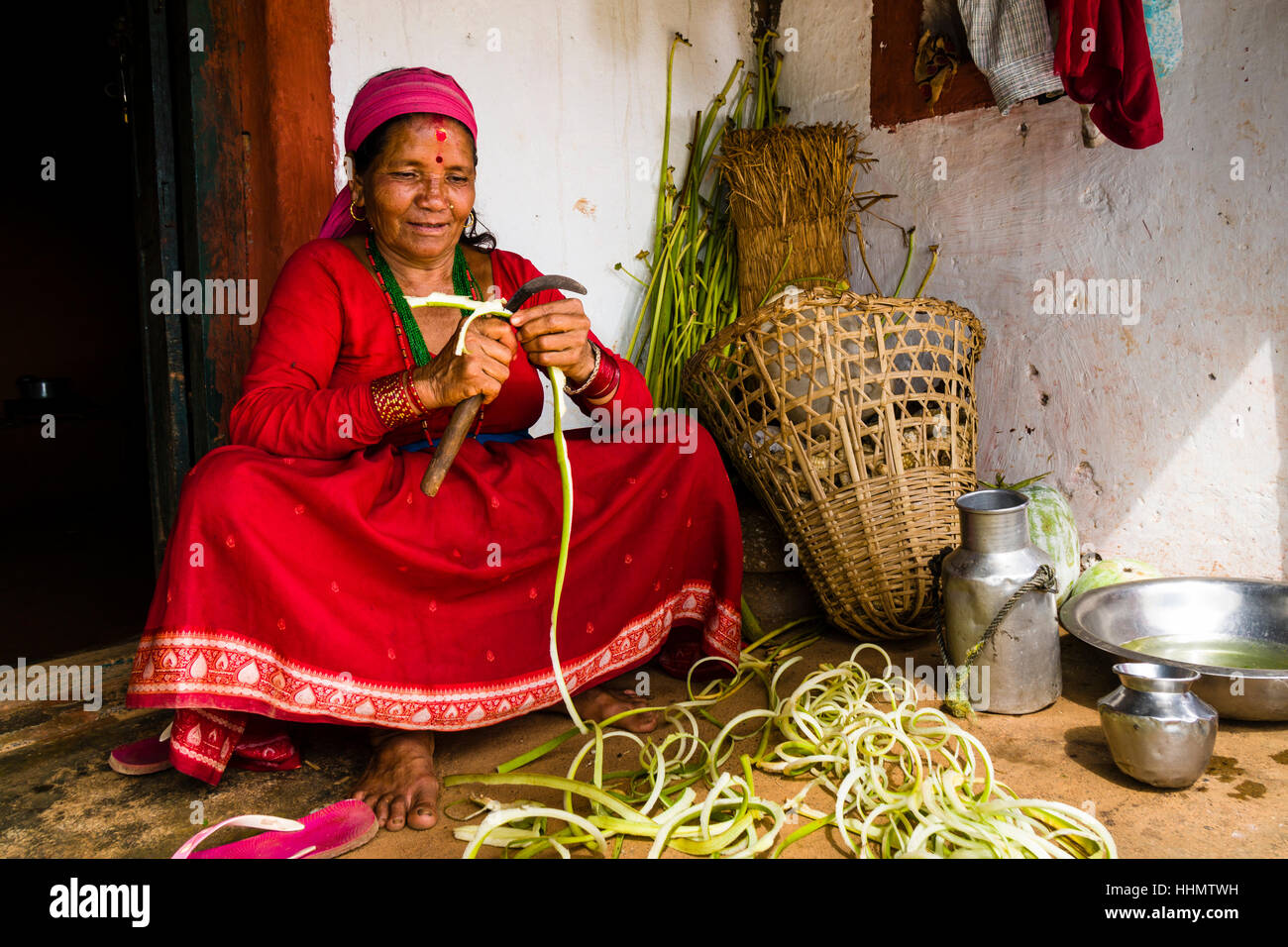 Native woman chopping vegetables in front of farmhouse, Tollogau, Kaski District, Nepal Stock Photo