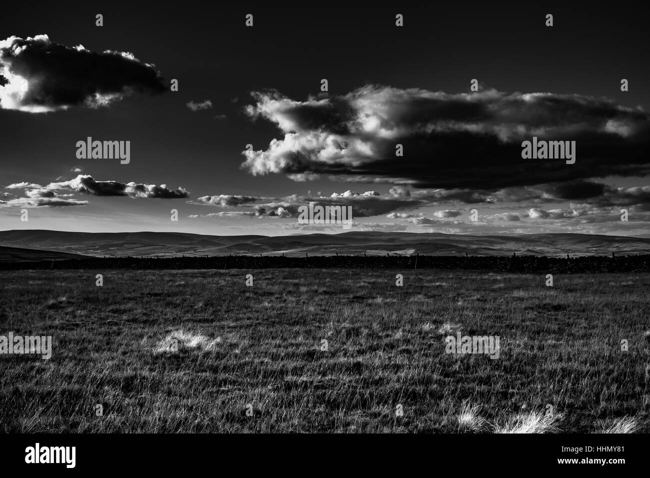 A view from Pendle Hill. Clouds cast shadows over hills. In distance Lake District mountains. Black and white. Forest Of Bowland. Lancashire. England Stock Photo
