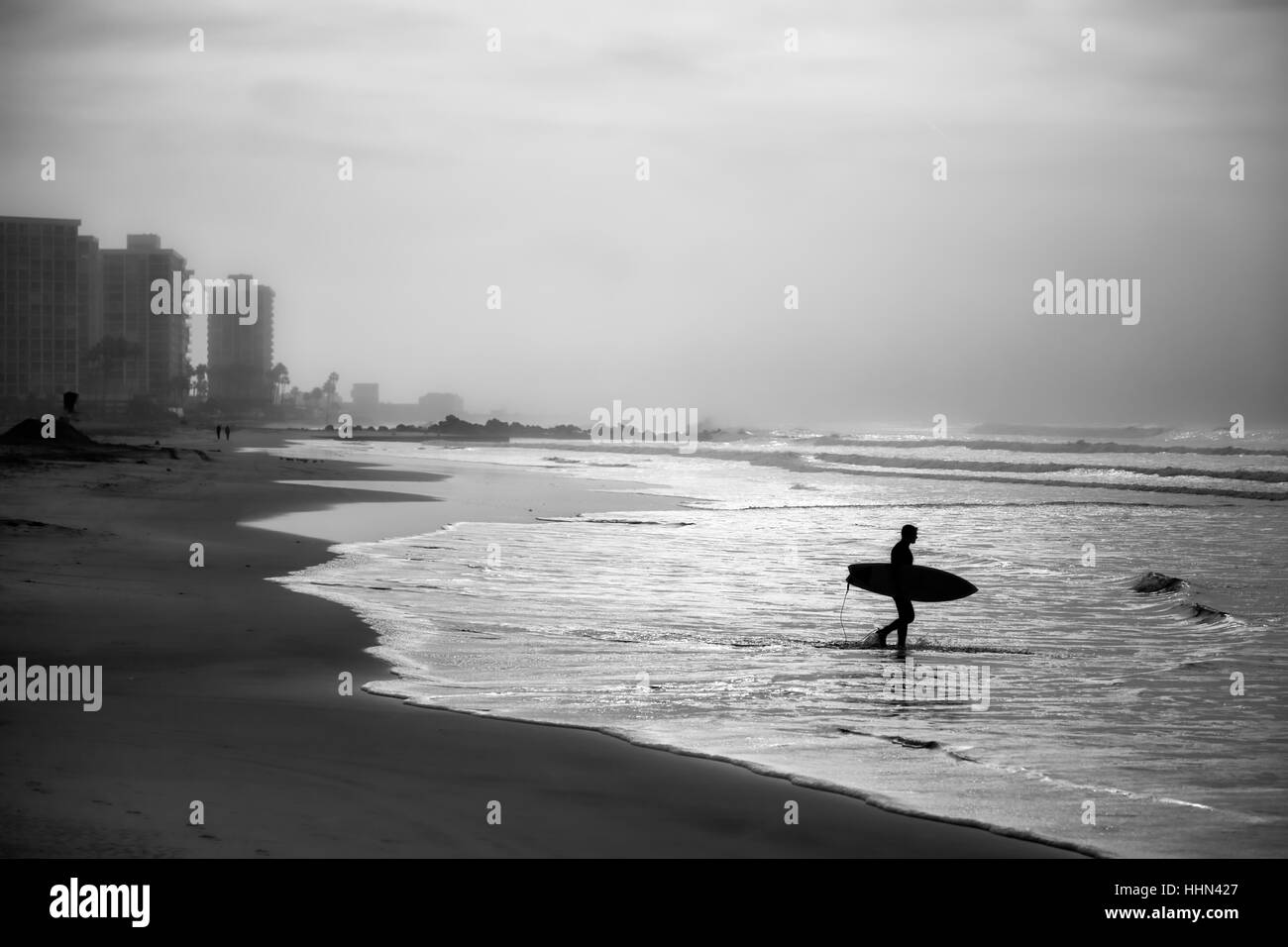 A morning surfer heads out to the ocean in Coronado, CA. Stock Photo