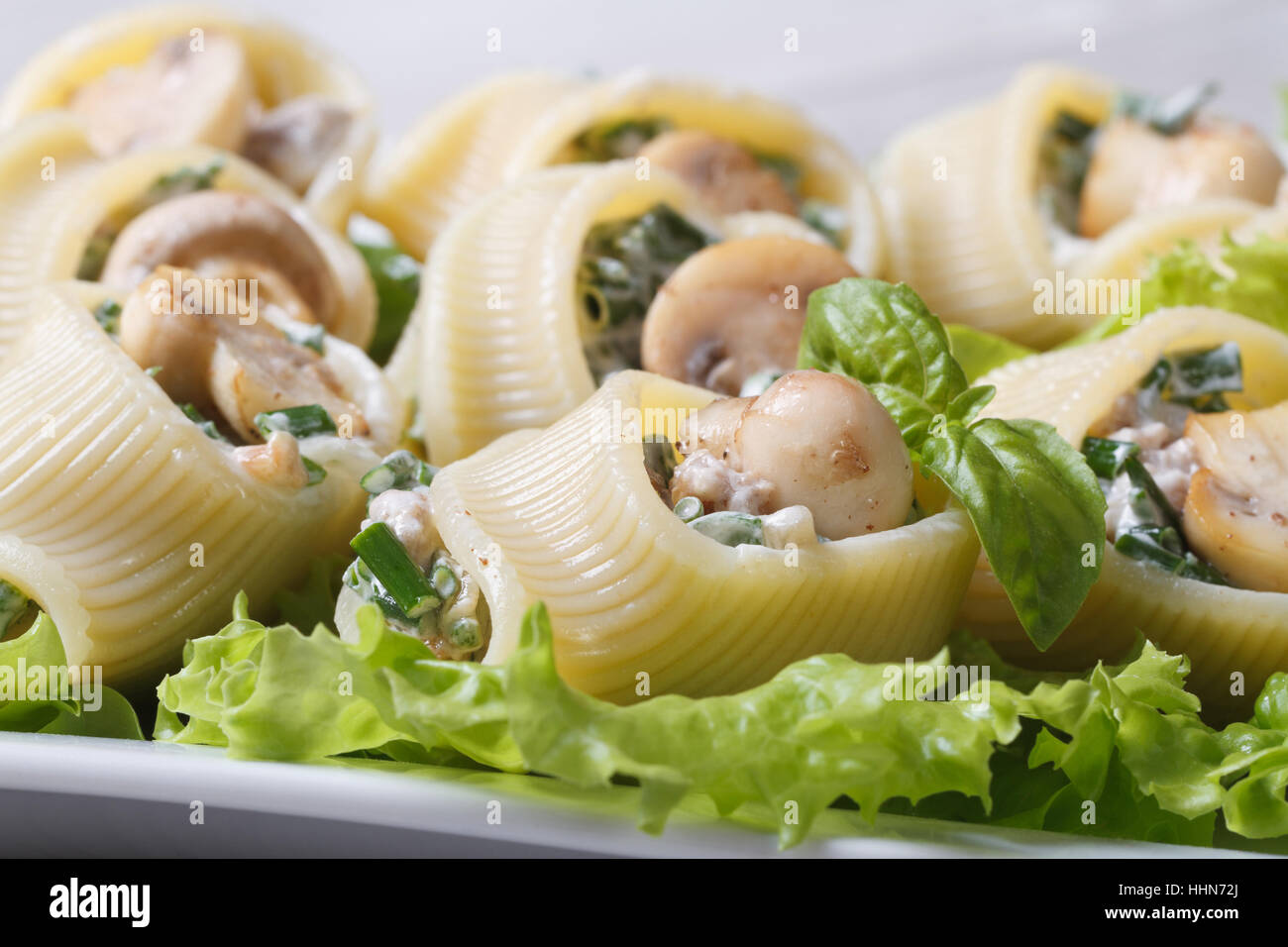 Lumakoni Italian pasta stuffed  mushrooms, cheese and spinach on a lettuce close up on a white plate horizontal Stock Photo