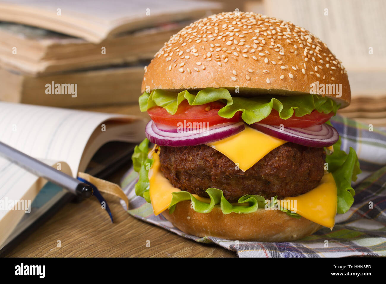 Lunch during study: Fresh big hamburger on a background of notebooks ...
