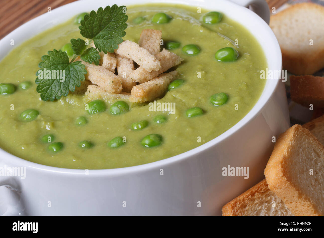 Cream soup with green peas with croutons closeup on a wooden table. horizontal Stock Photo