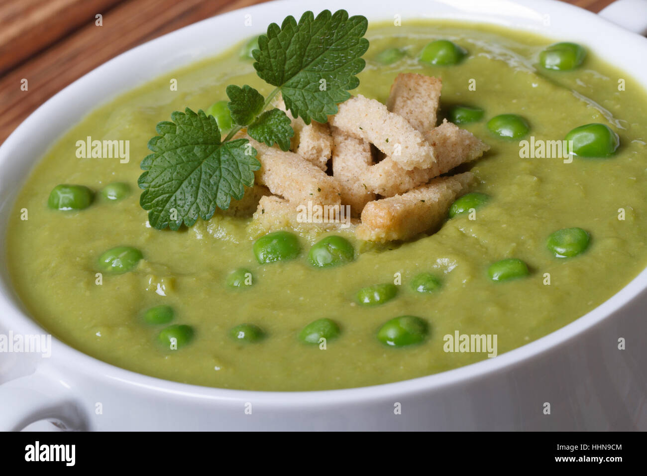 Cream soup with green peas and croutons macro. horizontal Stock Photo
