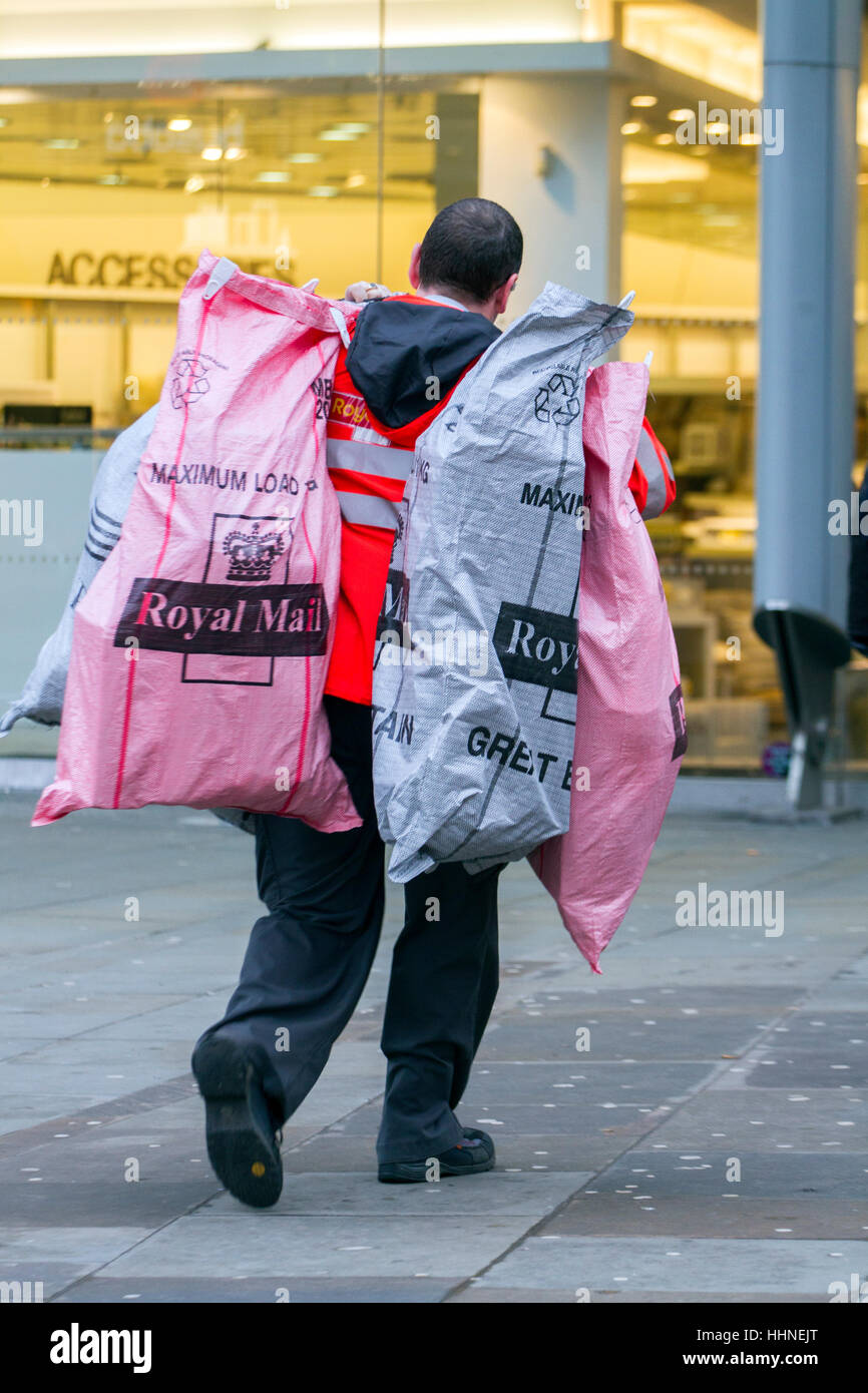 Postman carrying several royal mail parcel bags, UK Stock Photo - Alamy