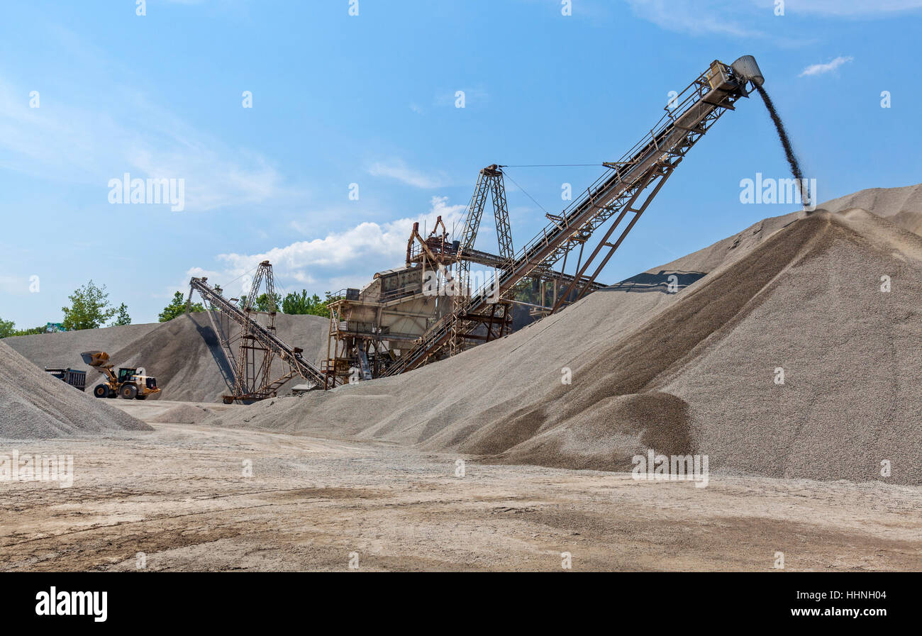 A conveyor belt transports crushed rock in a rock quarry into large