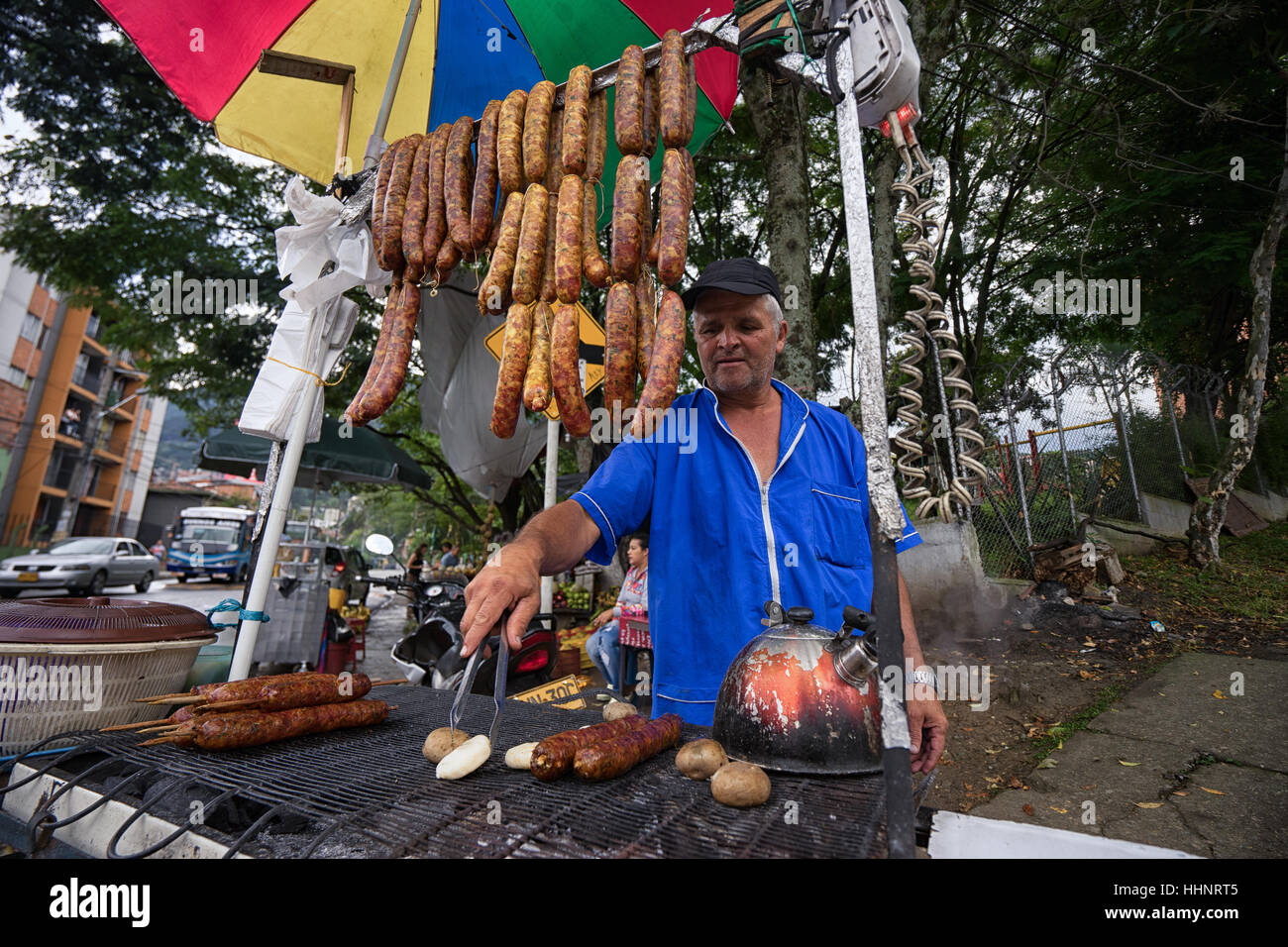 October 28, 2016 Medellin, Colombia: man frying sausages and potatoes at a roadside food stand, a popular economical fast food solution in Colombia Stock Photo