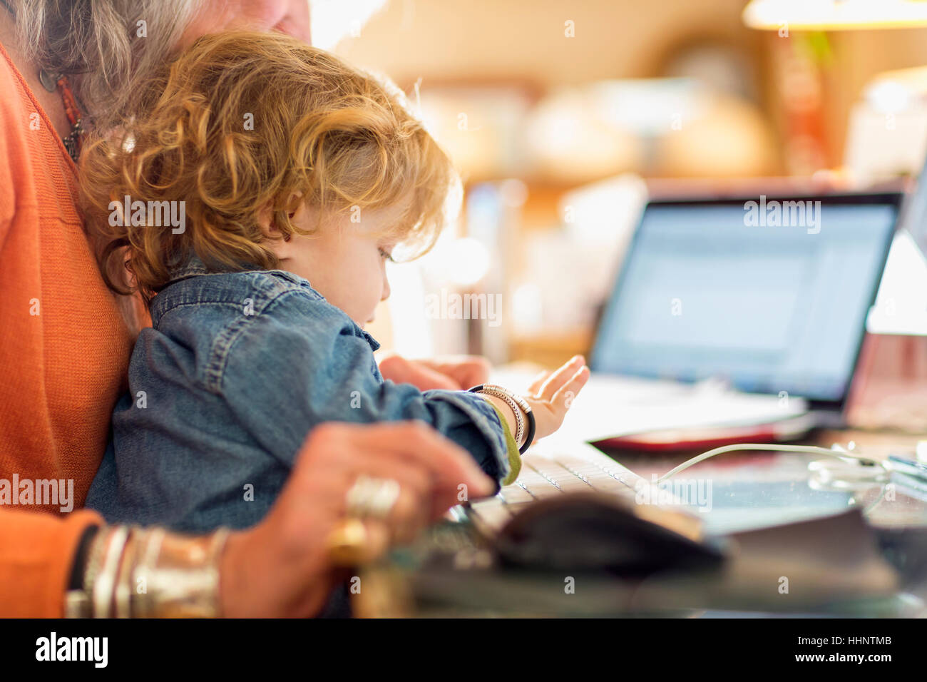 Caucasian baby boy in lap of grandmother using computer keyboard Stock Photo