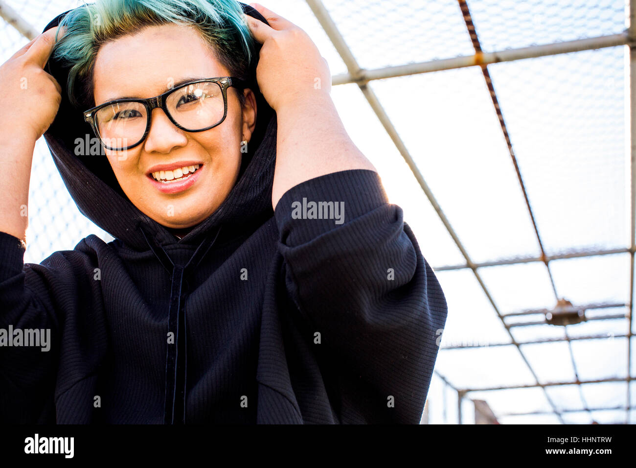 Portrait of smiling androgynous Asian woman wearing hoodie Stock Photo