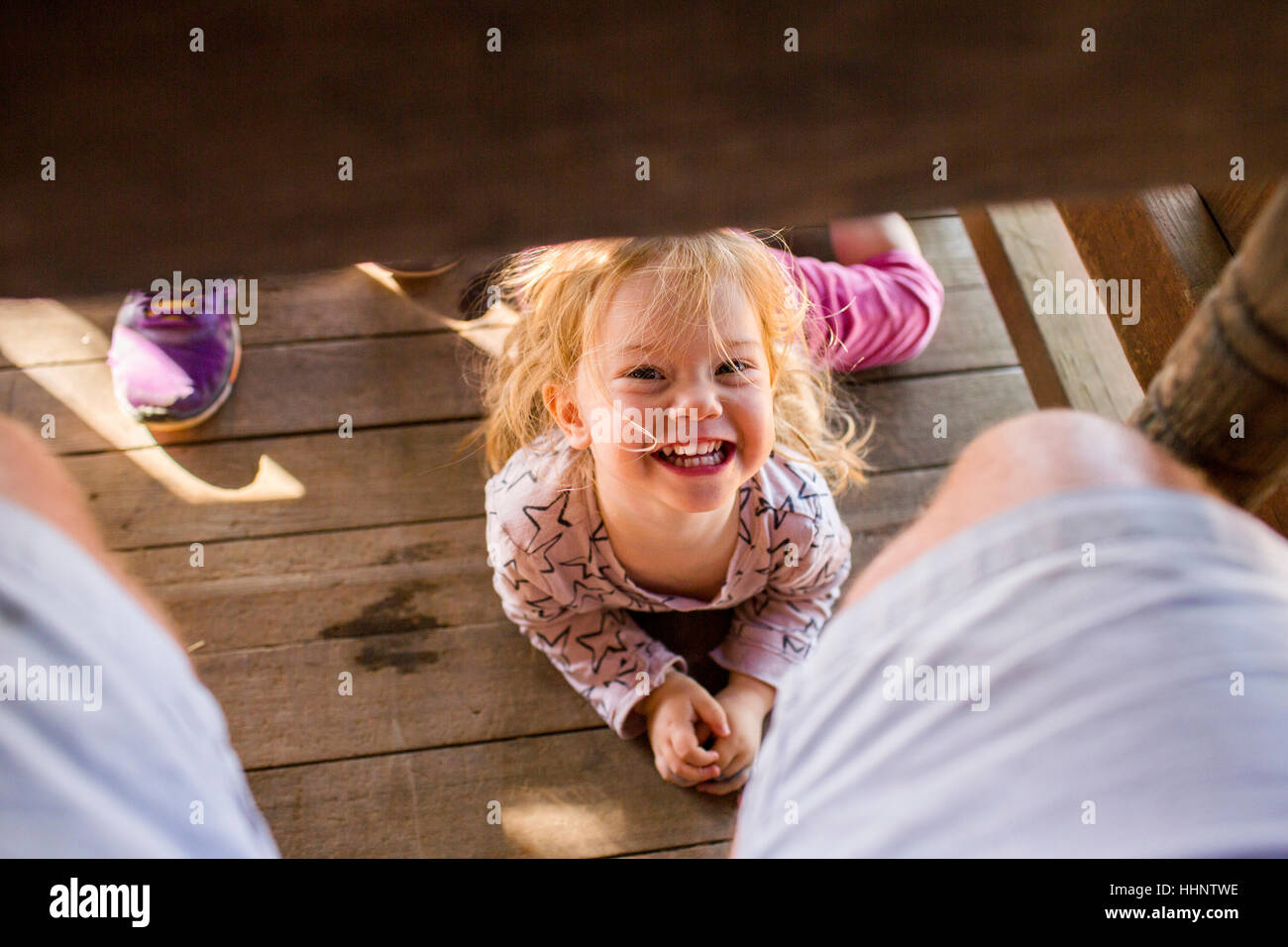 Portrait of smiling Caucasian girl laying underneath table Stock Photo