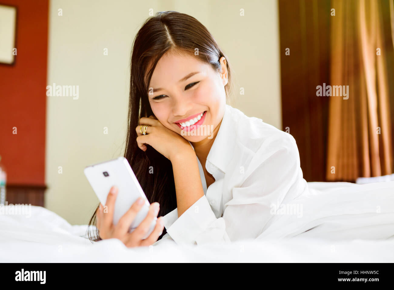 Smiling Asian teenage girl texting on cell phone Stock Photo