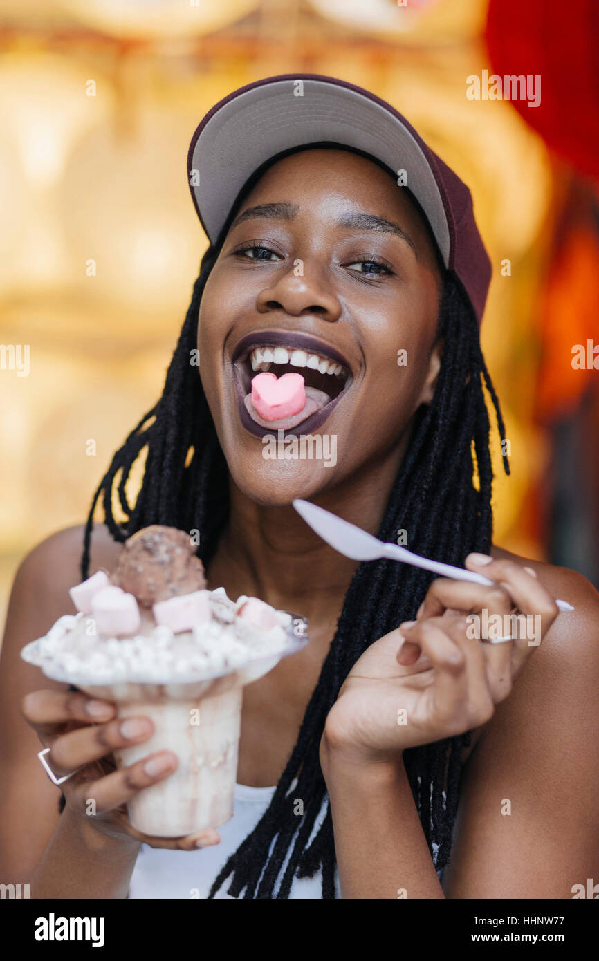 Mixed Race woman showing heart-shape candy on tongue Stock Photo