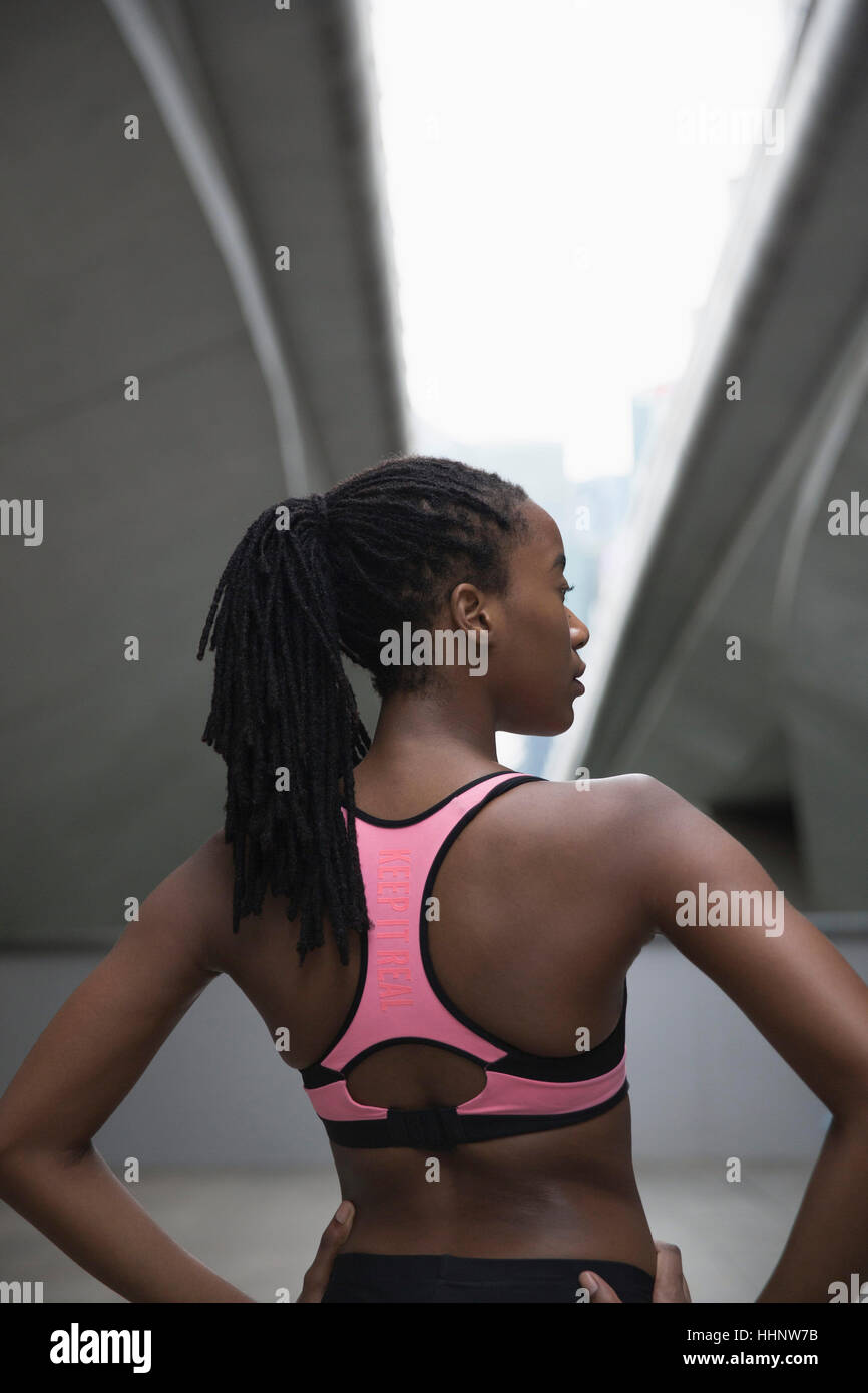 Mixed Race woman running standing under urban bridge Stock Photo