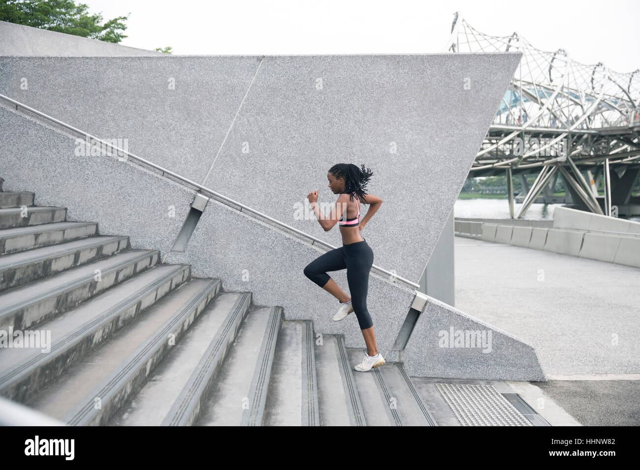 Mixed Race woman running up urban staircase Stock Photo