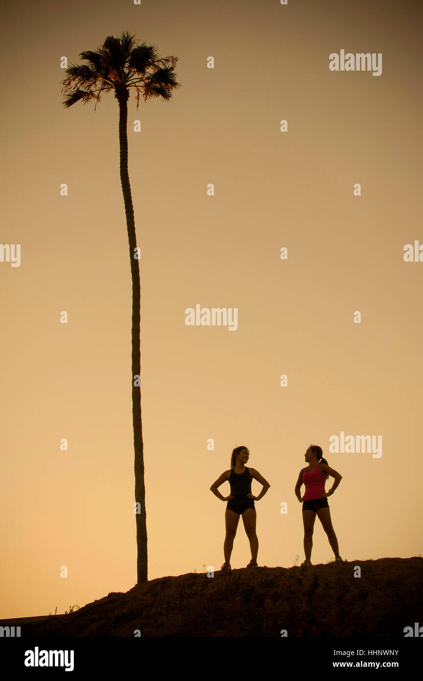 Mixed Race mother and daughter standing near palm tree Stock Photo