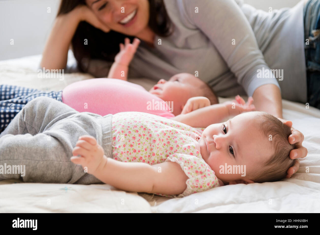 Caucasian mother caressing head of baby daughter on bed Stock Photo