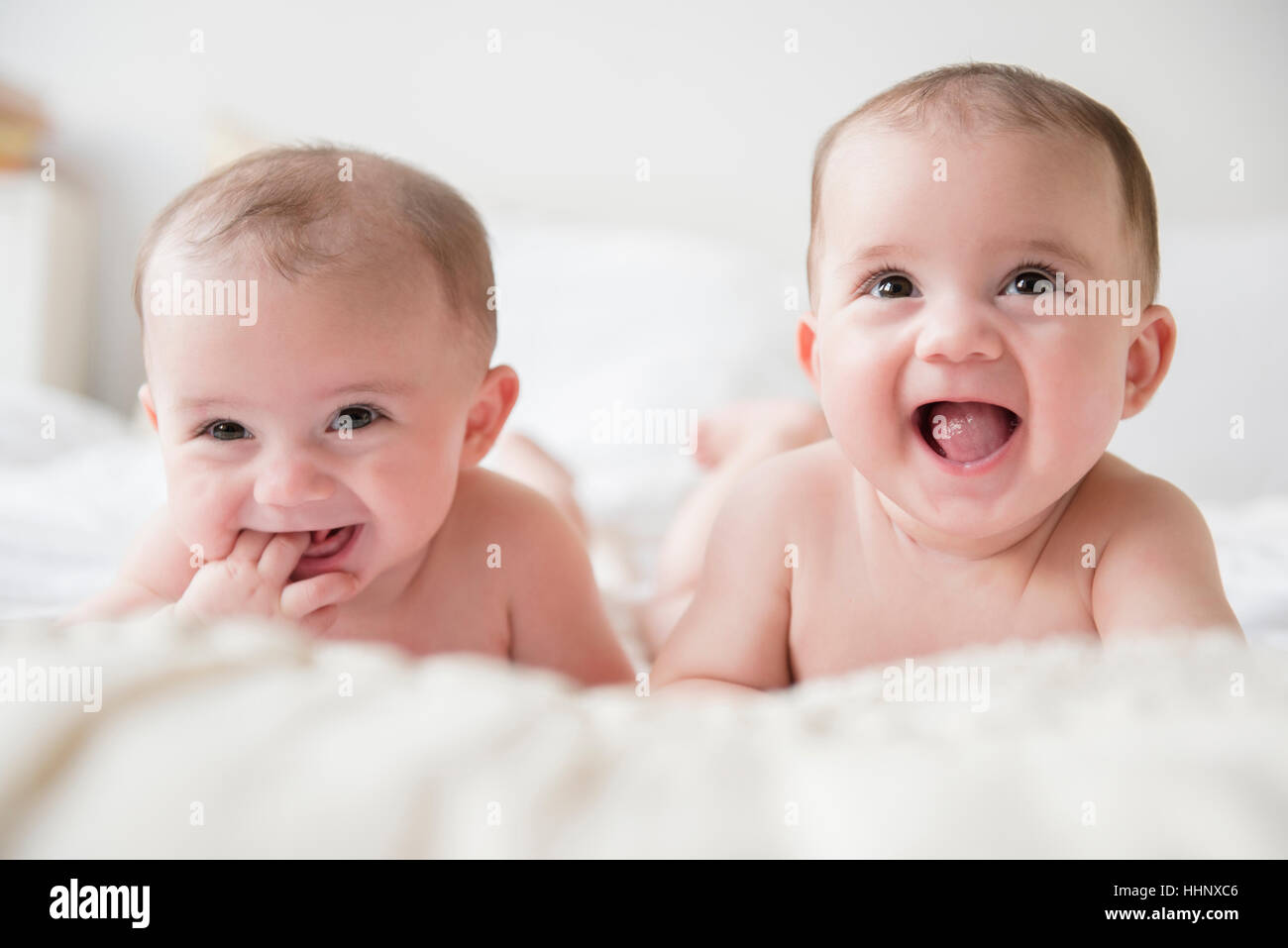 Caucasian twin baby girls smiling on bed Stock Photo Alamy