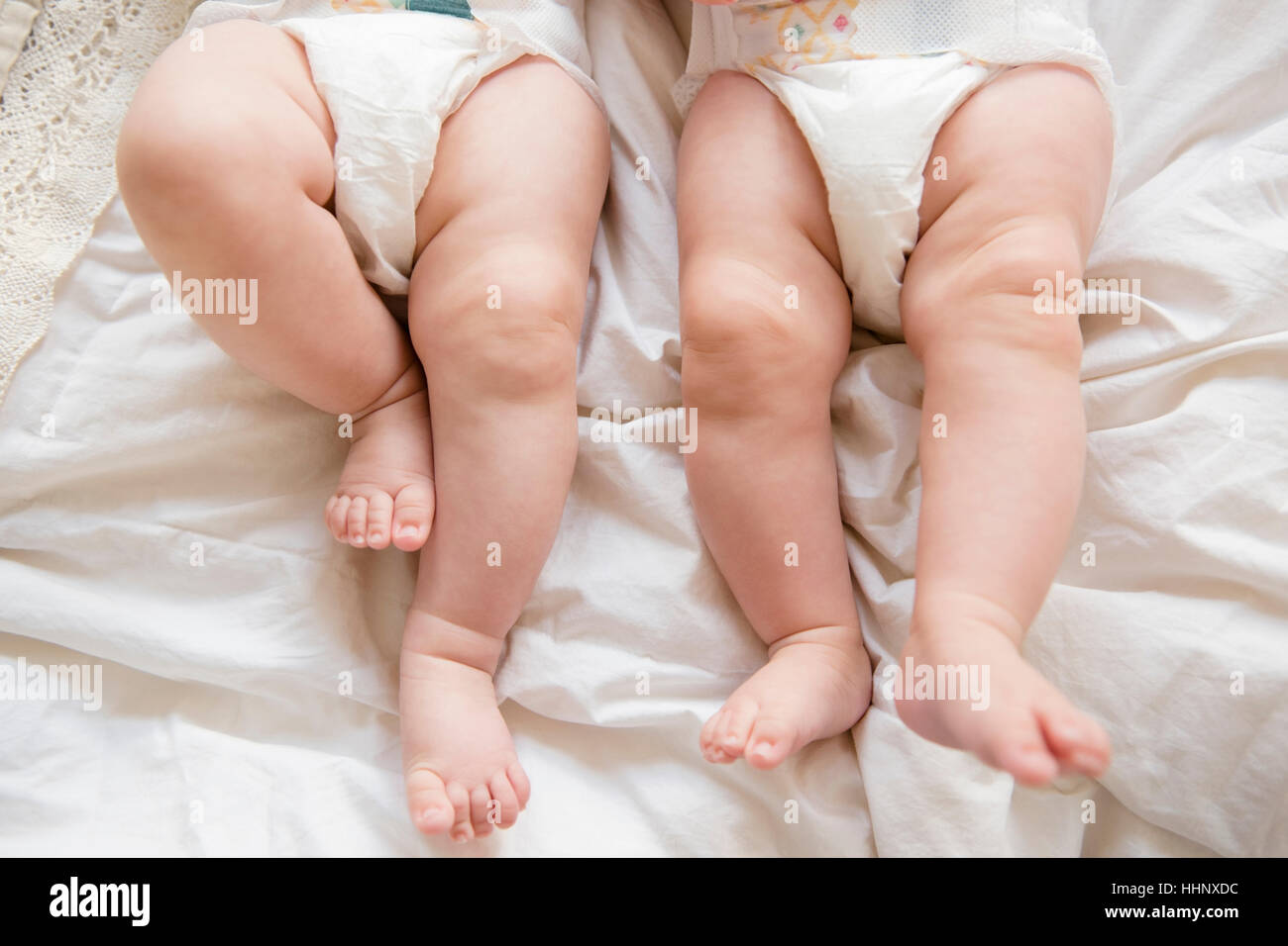 Legs of Caucasian twin baby girls laying on bed Stock Photo
