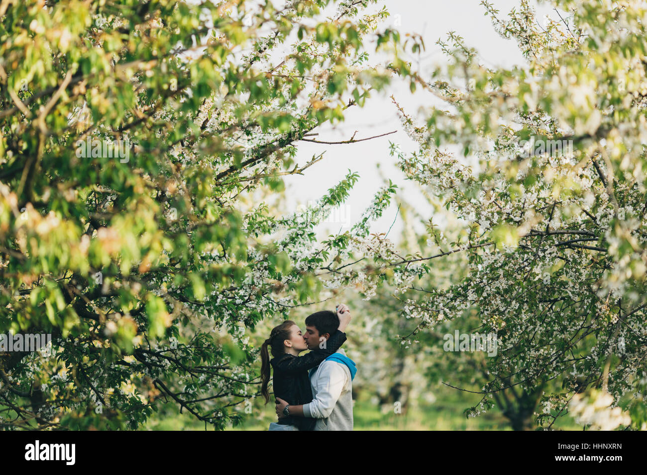 Caucasian couple kissing near trees Stock Photo