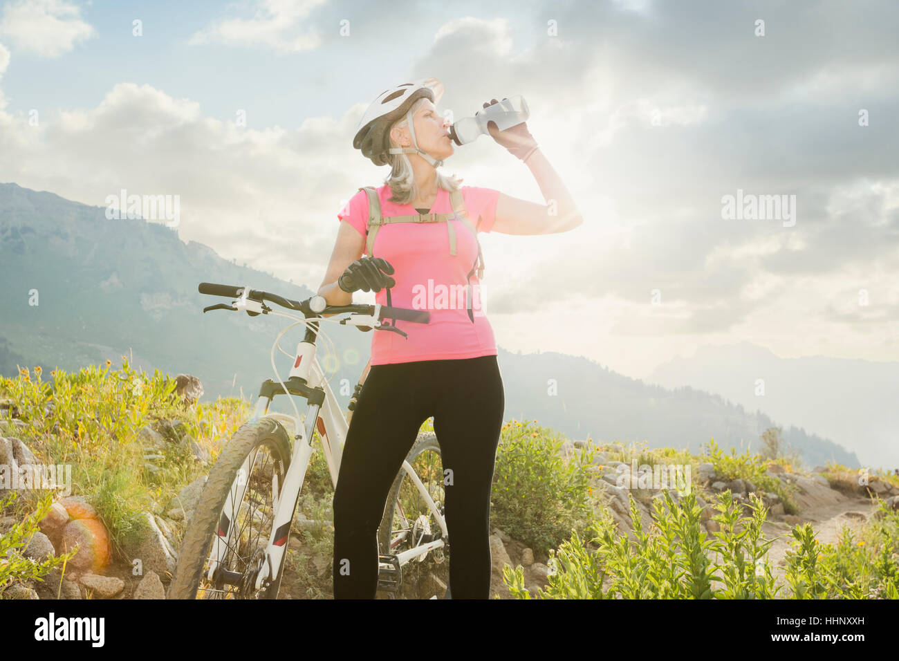 Caucasian woman with mountain bike drinking from bottle Stock Photo