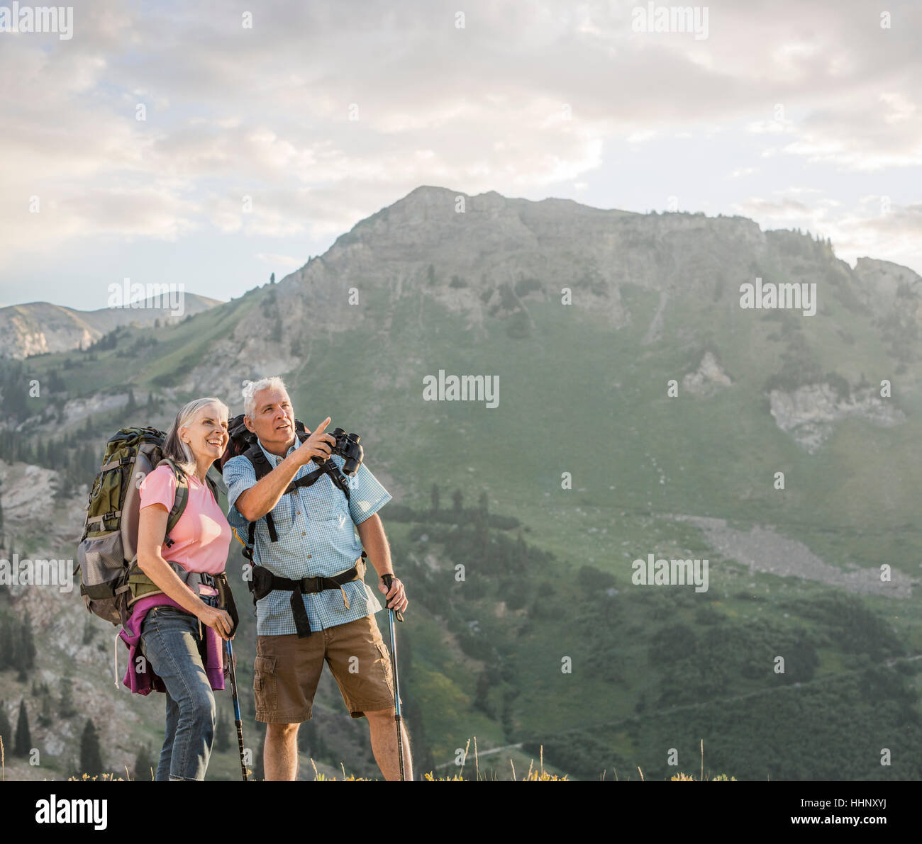 Caucasian couple with binoculars hiking on mountain Stock Photo