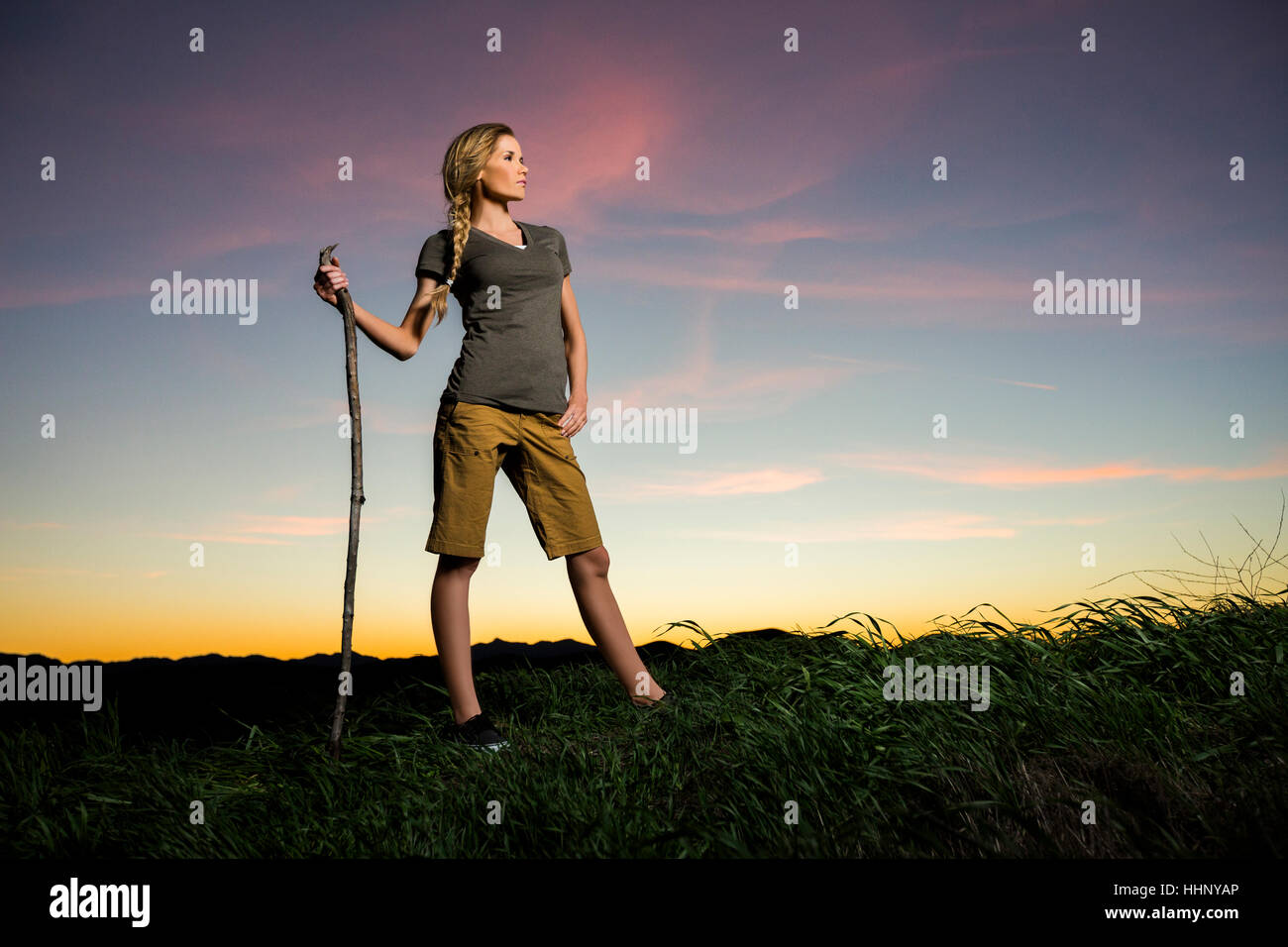 Caucasian woman holding walking stick at sunset Stock Photo - Alamy