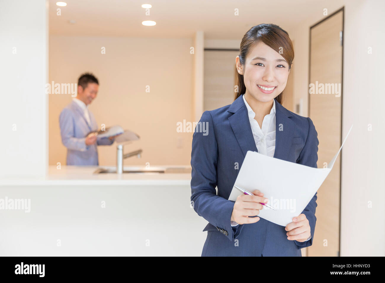 Woman Smiling to the Camera with Floor Plan Stock Photo
