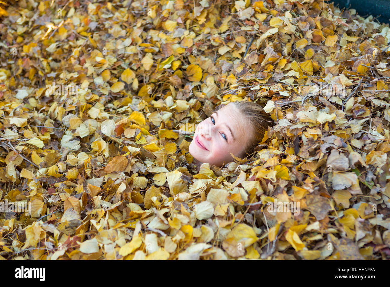 Face of Caucasian girl playing in autumn leaves Stock Photo - Alamy