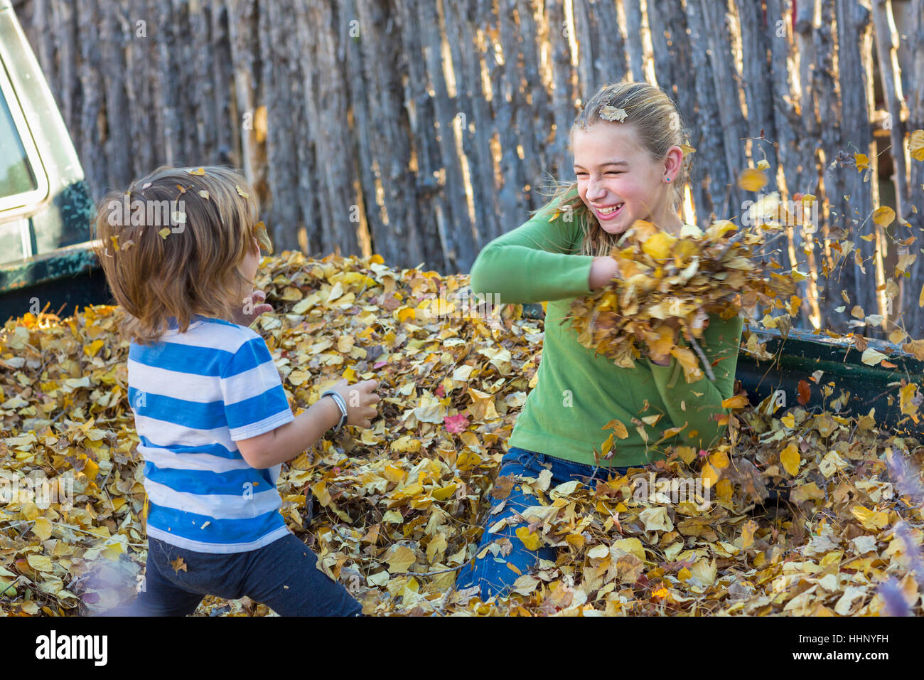 Caucasian brother and sister throwing autumn leaves Stock Photo