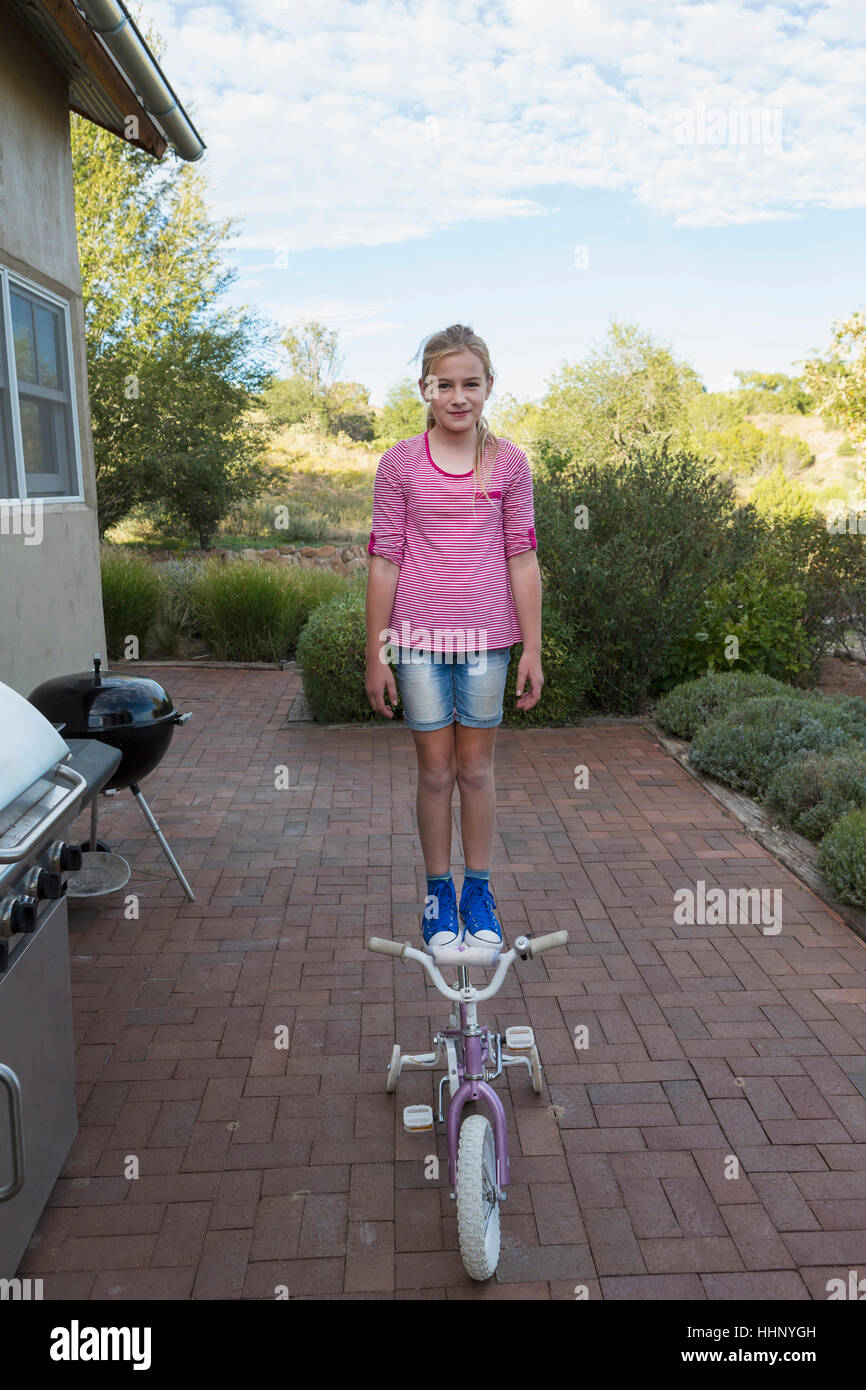Caucasian girl standing on seat of bicycle Stock Photo Alamy