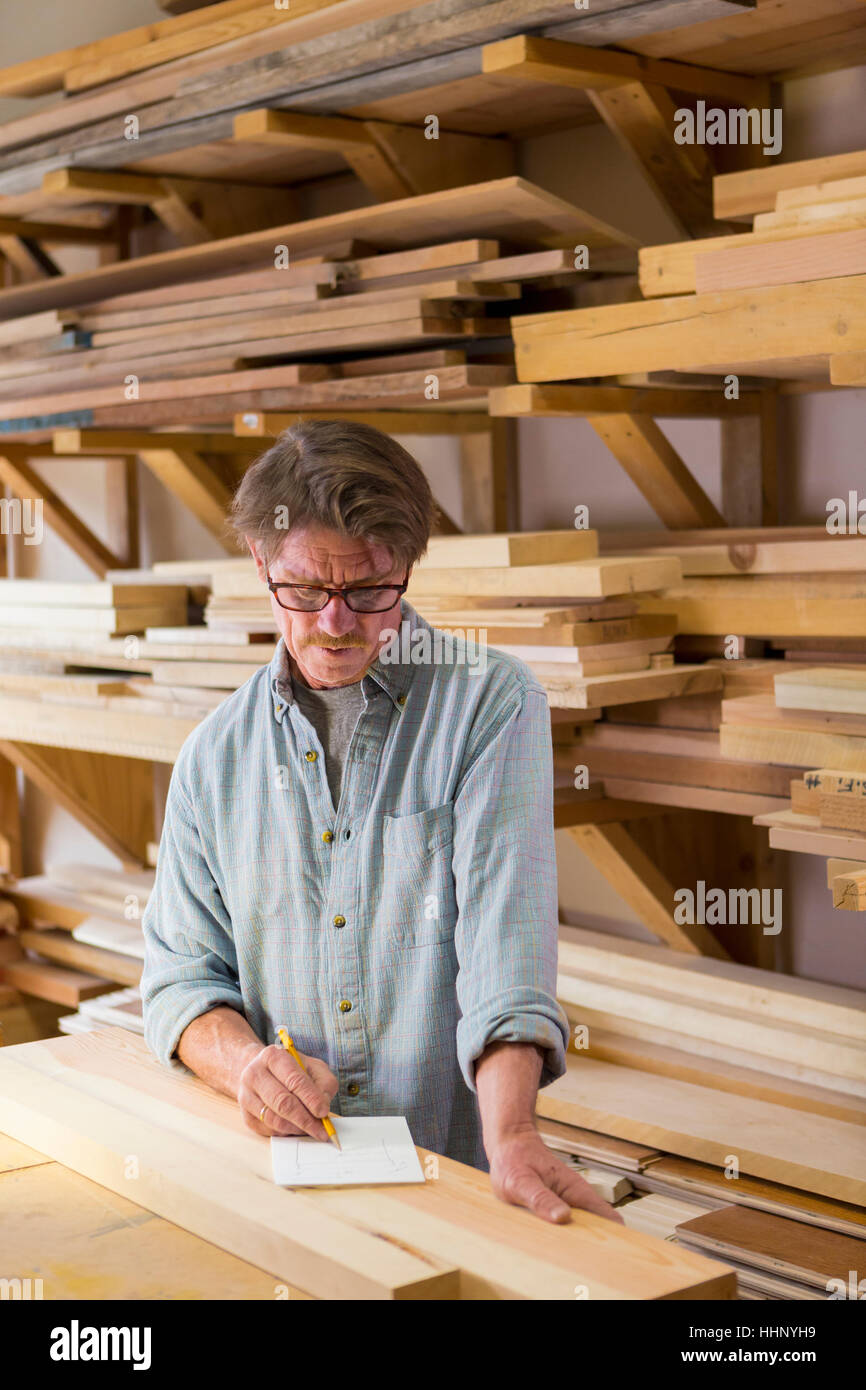 Caucasian carpenter writing on notepad in workshop Stock Photo