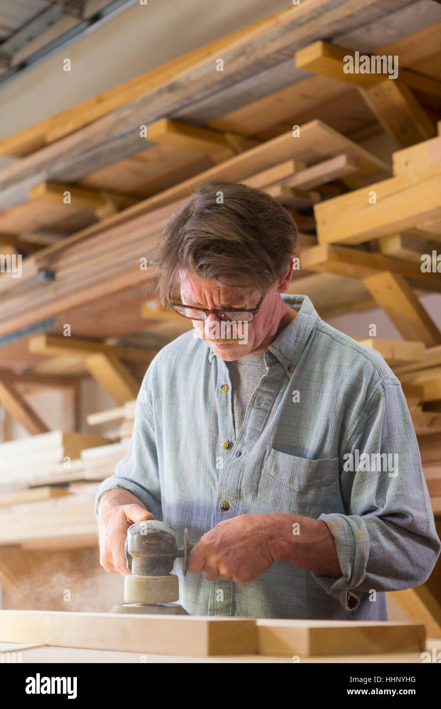 Caucasian carpenter sanding wood in workshop Stock Photo