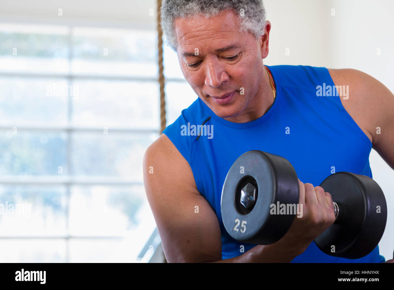 Mixed Race man curling dumbbell Stock Photo