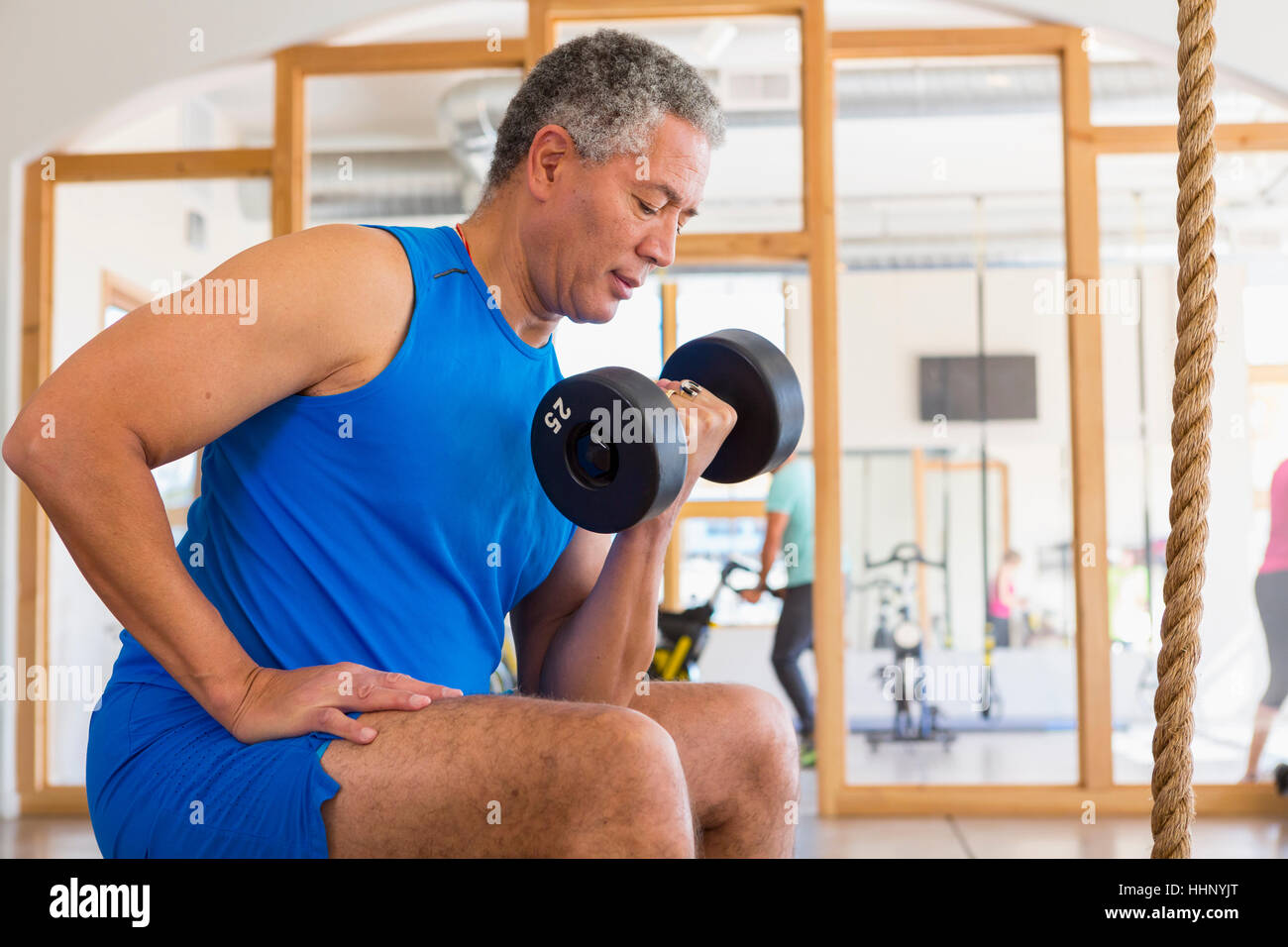 Mixed Race man curling dumbbell in gymnasium Stock Photo