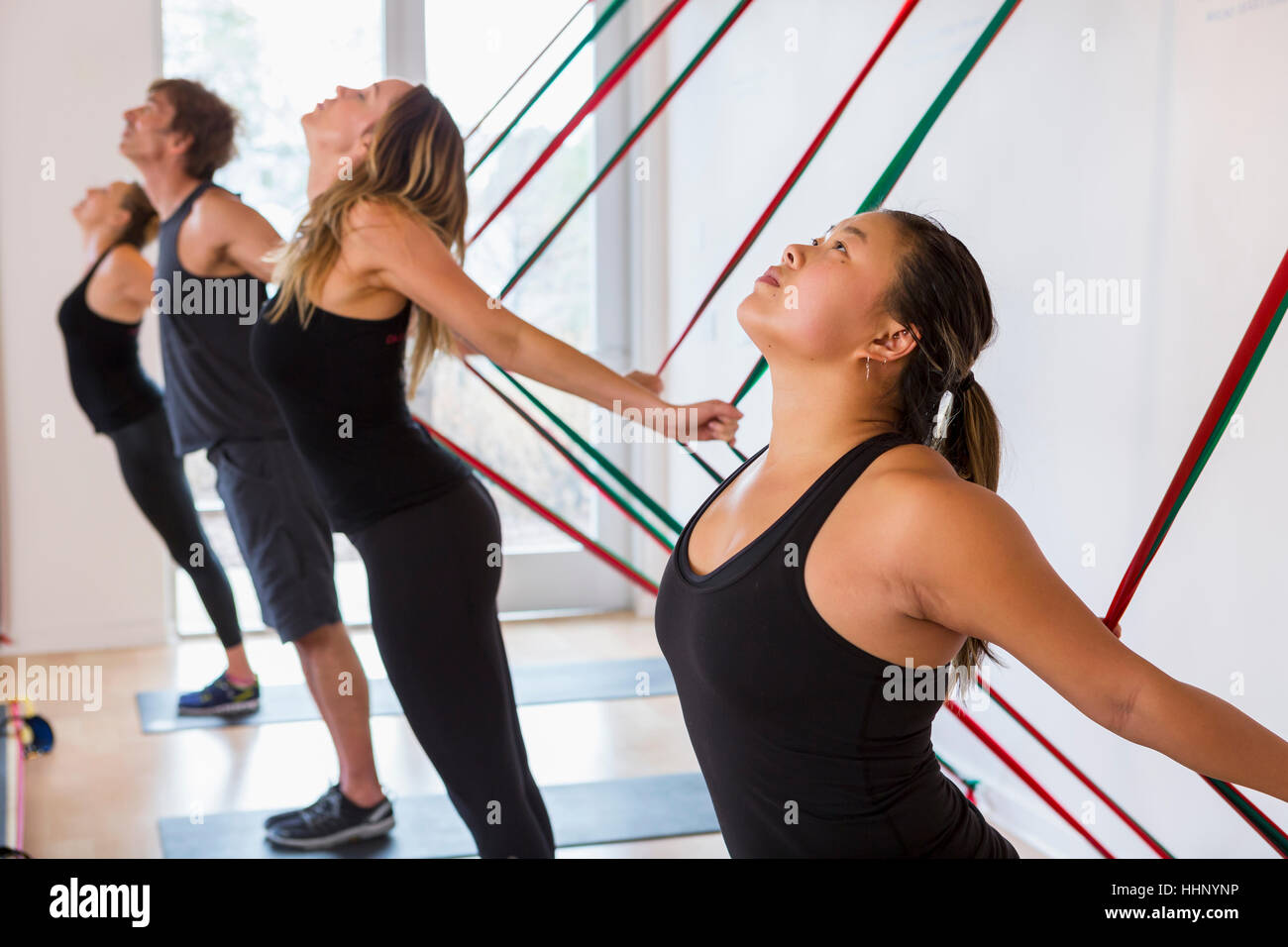 People pulling on resistance bands in gymnasium Stock Photo