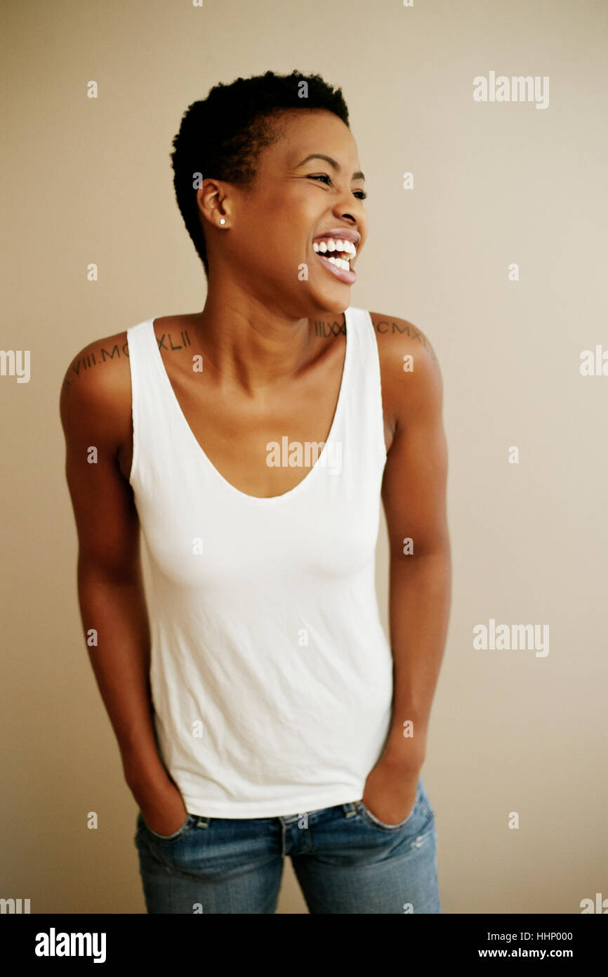 Portrait of laughing Black woman with hands in pockets Stock Photo