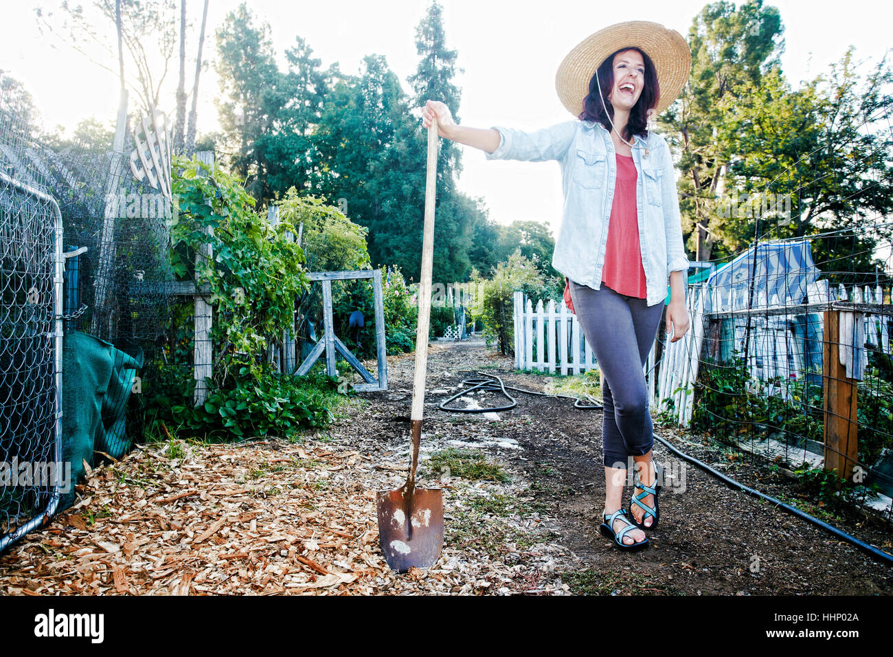 Laughing Caucasian woman leaning on shovel in garden Stock Photo