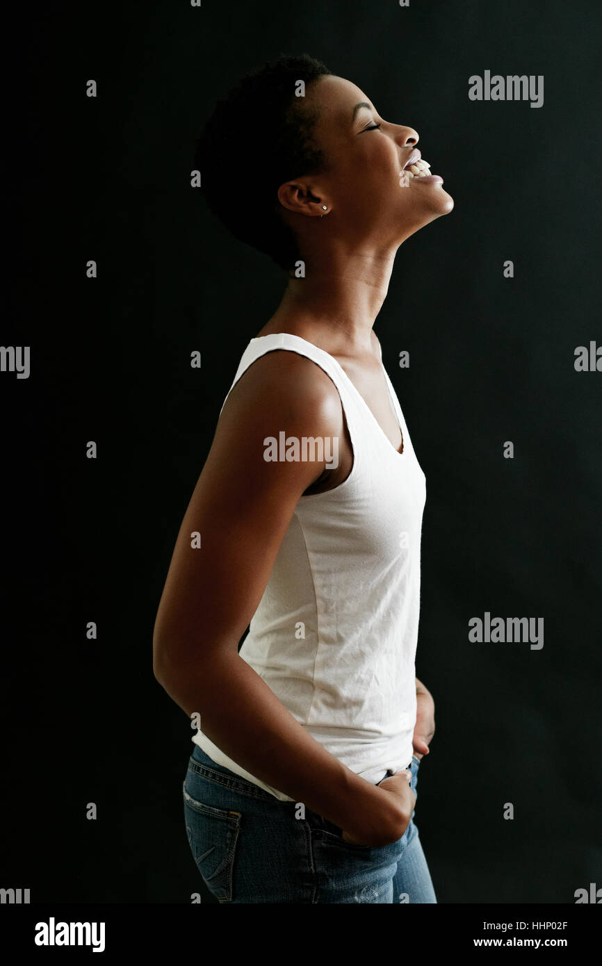 Black woman standing and laughing with hands in pockets Stock Photo