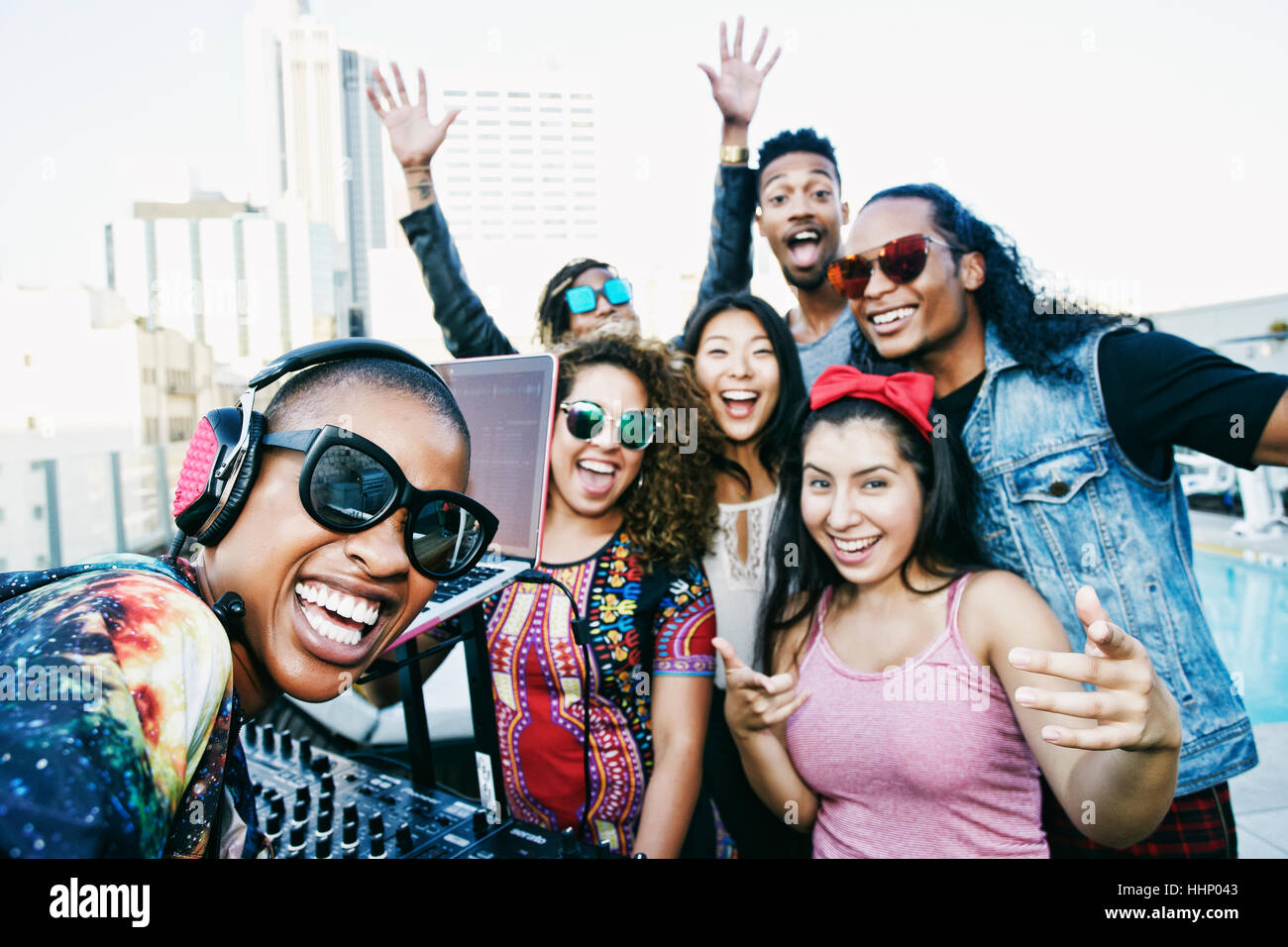 Friends smiling with DJ on urban rooftop Stock Photo - Alamy