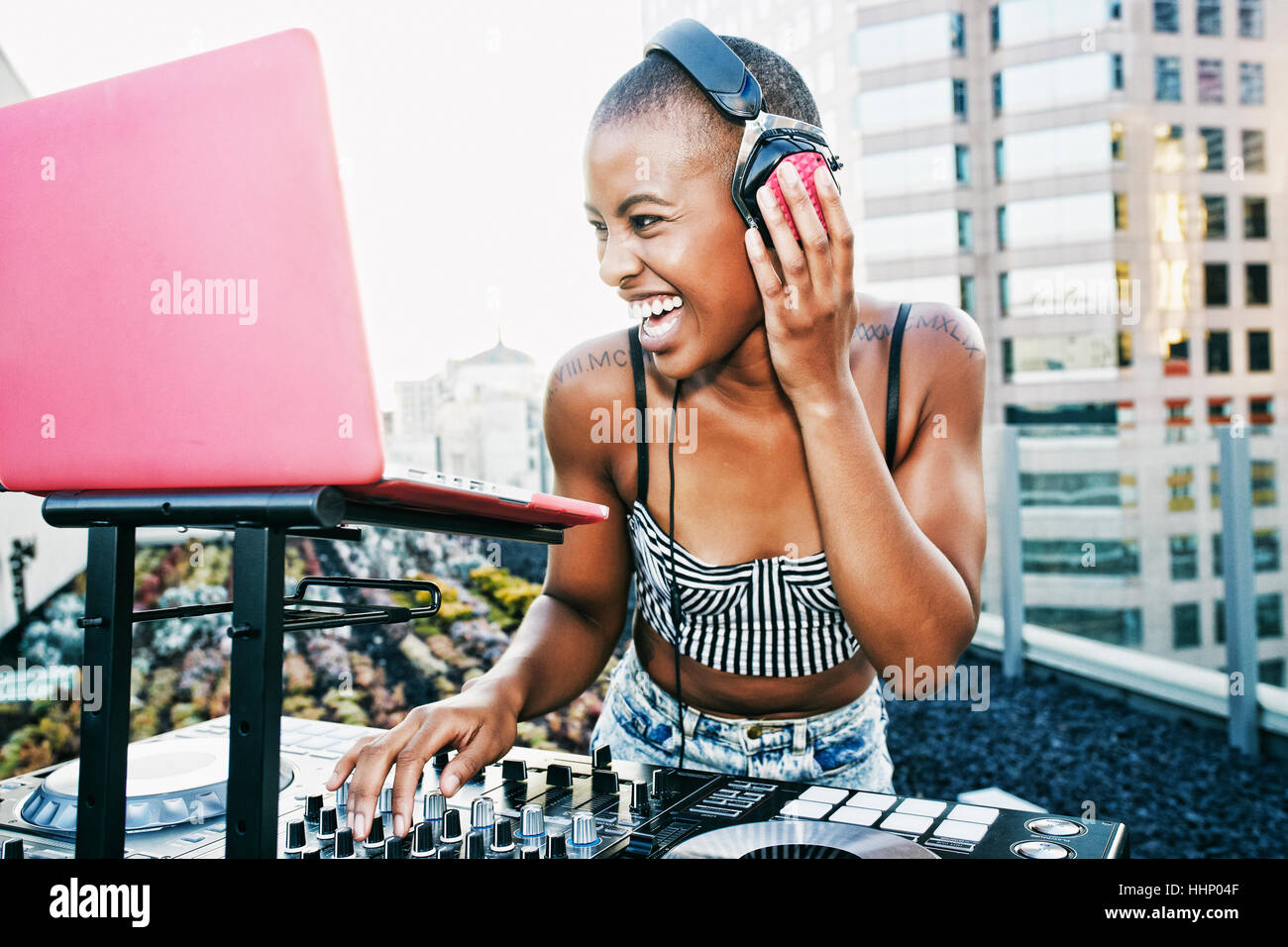 Black DJ laughing on urban rooftop Stock Photo