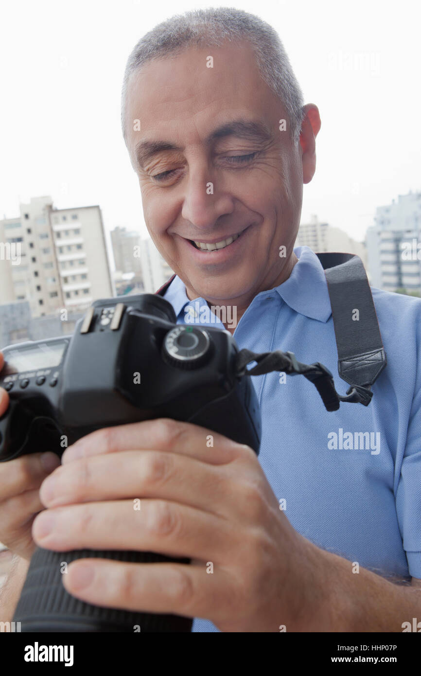 Hispanic man examining photograph on digital camera Stock Photo
