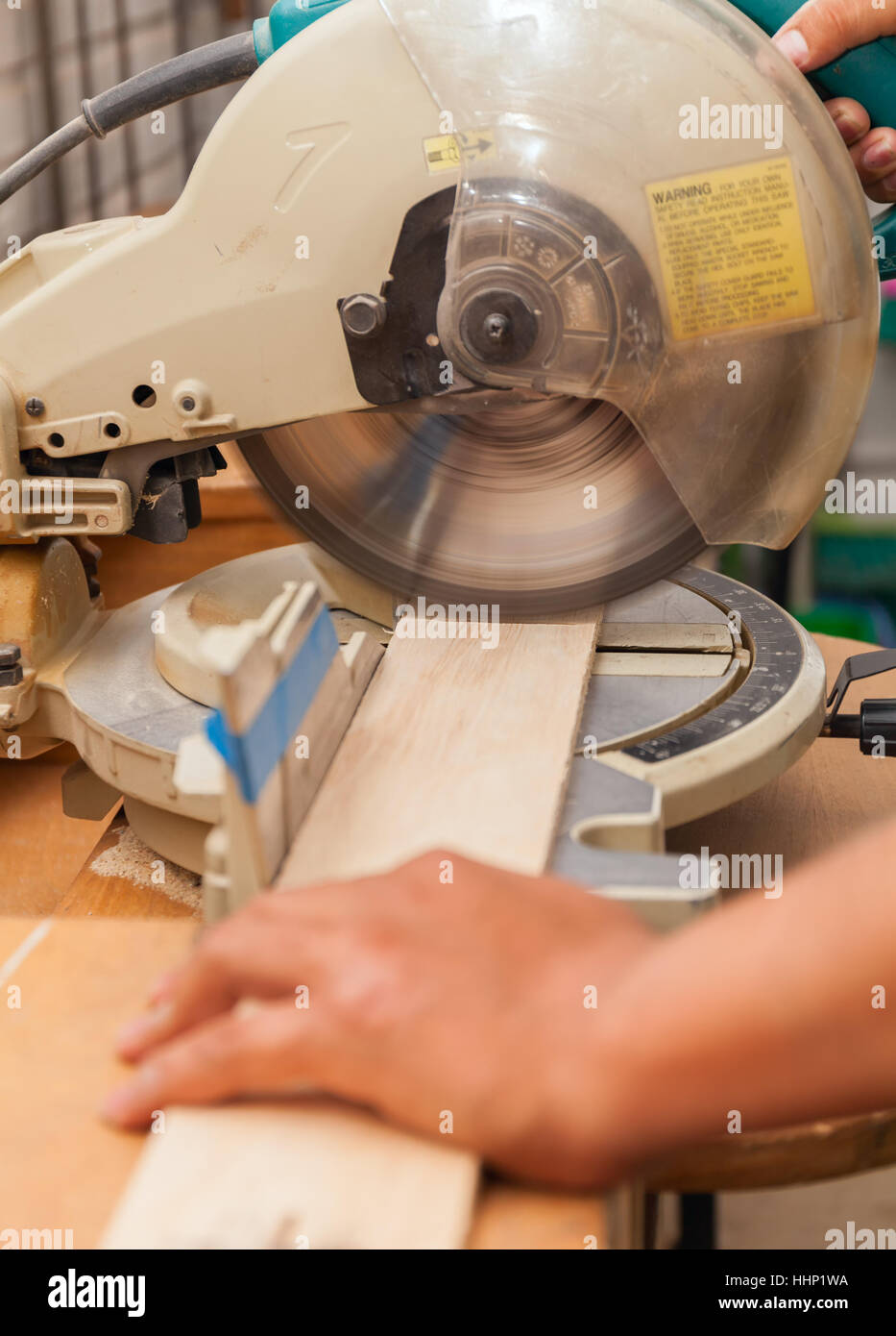 carpenter's hands on wood at table saw making a cut Stock Photo