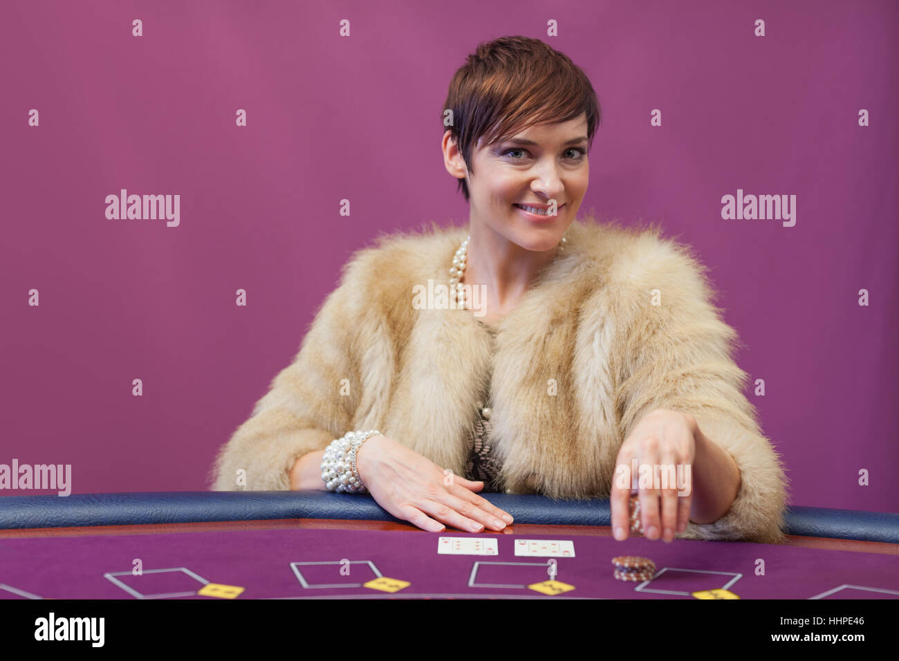 Woman sitting in a casino at table while stacking chips and placing cards Stock Photo
